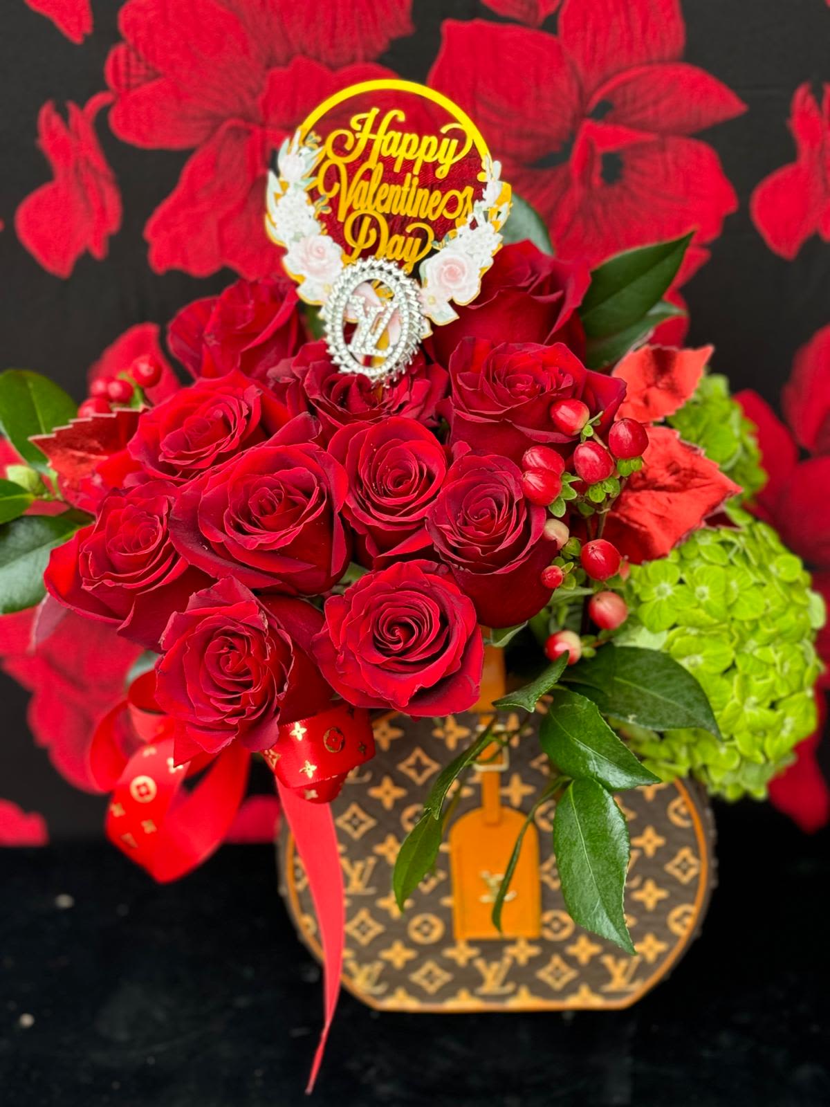 Designer Touch - Set in a designer-inspired base with the iconic LV monogram print, this piece combines vibrant red roses and soft hydrangeas with high-end fashion for a bold and sophisticated look.