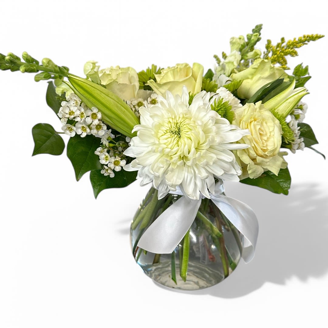 Emerald Elegance - This stunning vase arrangement features an enchanting blend of white and green blooms that exude elegance and vibrancy. At the center, the crisp white Asiatic lilies and football mums create a striking focal point, surrounded by the delicate white snapdragons that rise gracefully above the lush greenery. Incorporating white-green roses and carnations adds depth and texture, while cheerful green button flowers provide playful accents. Cascading down are the unique bells of Ireland, lending a whimsical touch, complemented by the soft, glossy salal tips that frame the arrangement beautifully. This captivating display is perfect for brightening up any space or celebrating special occasions.