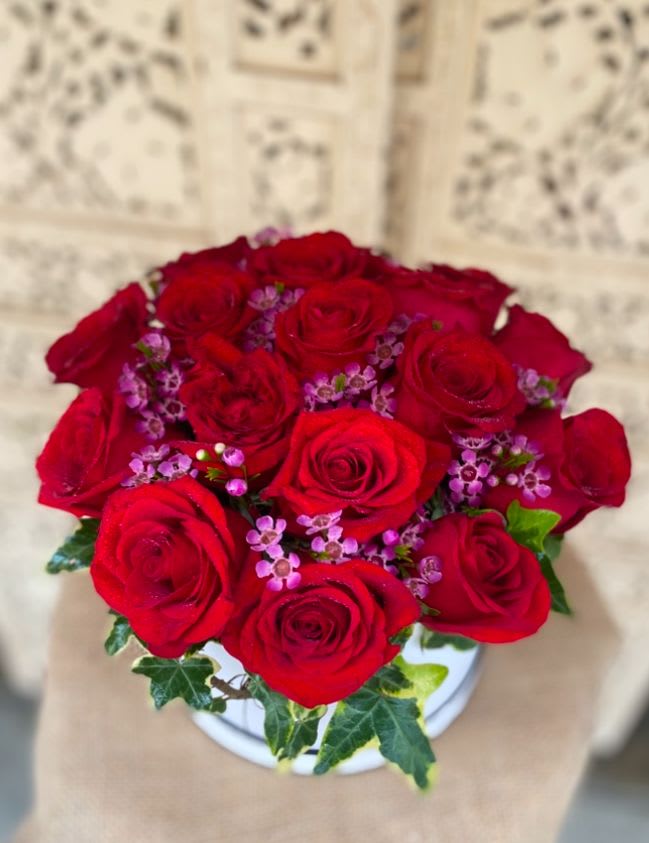 Red Rose Box - A dozen, big velvety roses in a round hat box. Finished off with garden ivy and wax flower.
