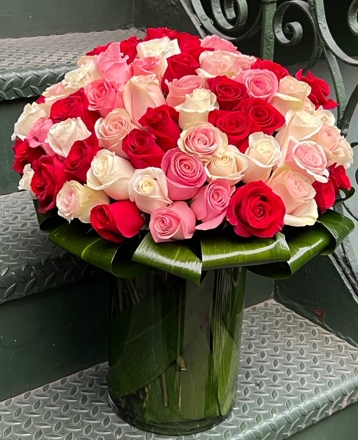 Valentine's Day 100 Mixed Roses Valentine's Day 100 Mixed Roses - A crystal vase overflowing with 100 beautiful lush pink, ivory and red long stemmed roses. Surrounded by flat greens this arrangement makes the boldest statement of love. Blissful joy guaranteed!