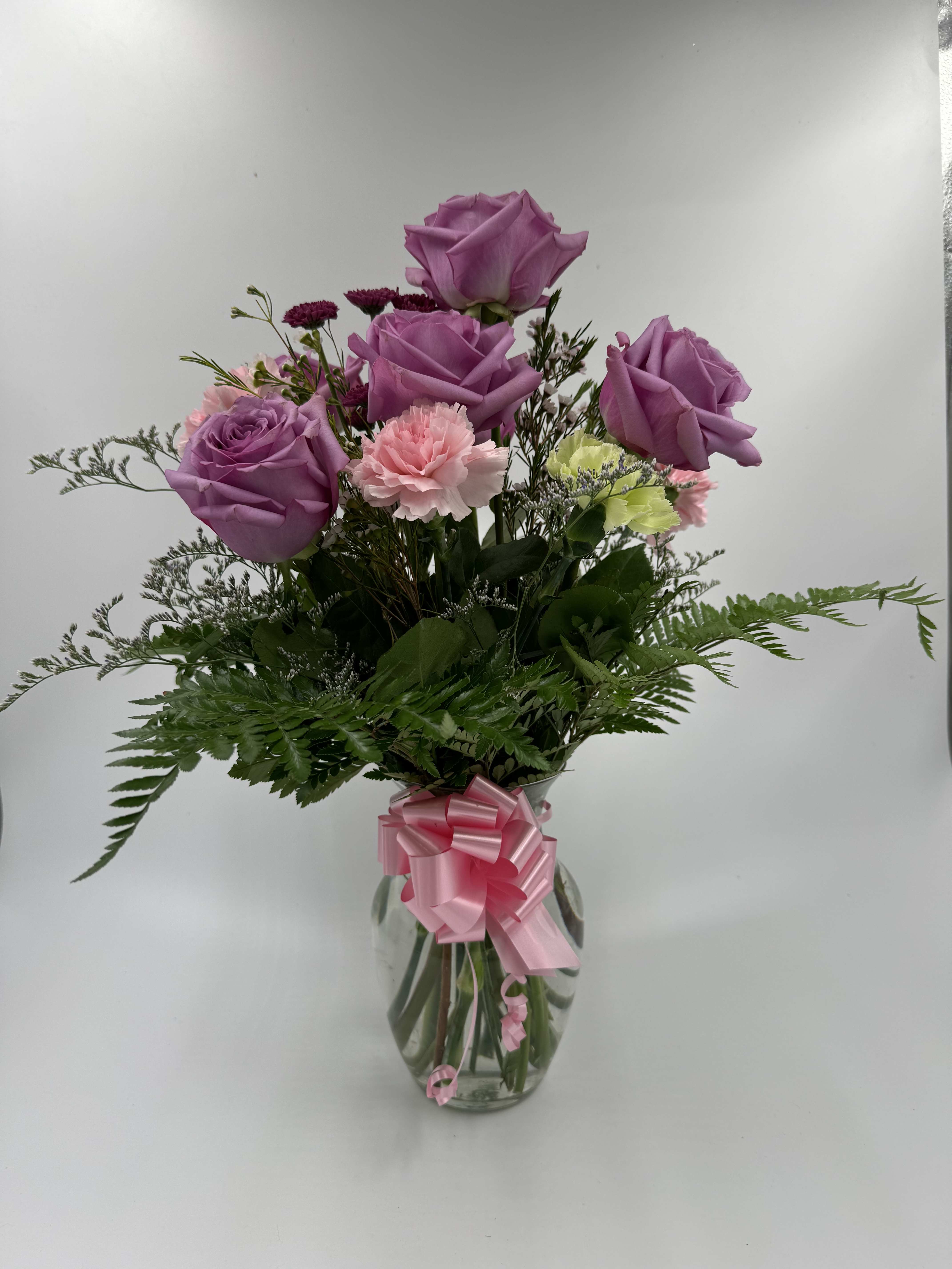 Jardin Morado - This arrangement comes in a glass vase with a bow in the front, and includes 6 roses, leather leaf, carnations, etc..