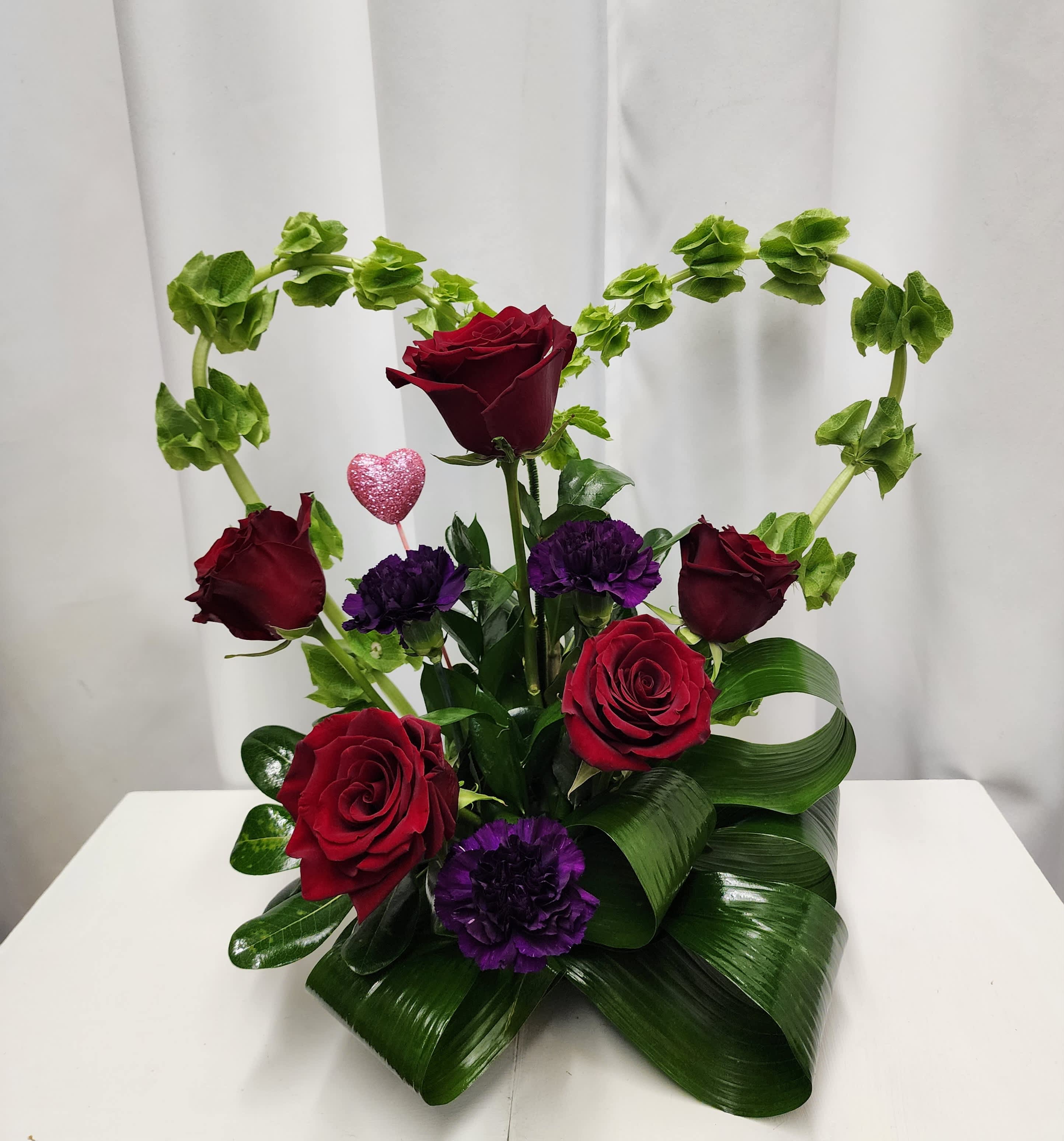 Heart Of My Heart - A beautiful display of roses, florigiene carnations and bells of ireland create a stunning display that says love and Happy Valentine's without words.   Color of roses and carnations can be changed. Place your request in the notes section to florist. 