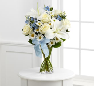 The FTD® Sweet Peace™ Bouquet - The FTD® Sweet Peace™ Bouquet is an elegant way to convey your deepest sympathies for the loss of their child. White roses, daisies, and Oriental lilies are sweetly accented with light blue delphinium, lush greens and a light blue organza ribbon, arranged to perfection in a clear glass vase, to create an exquisite way to offer comfort during this time of grief and sadness.