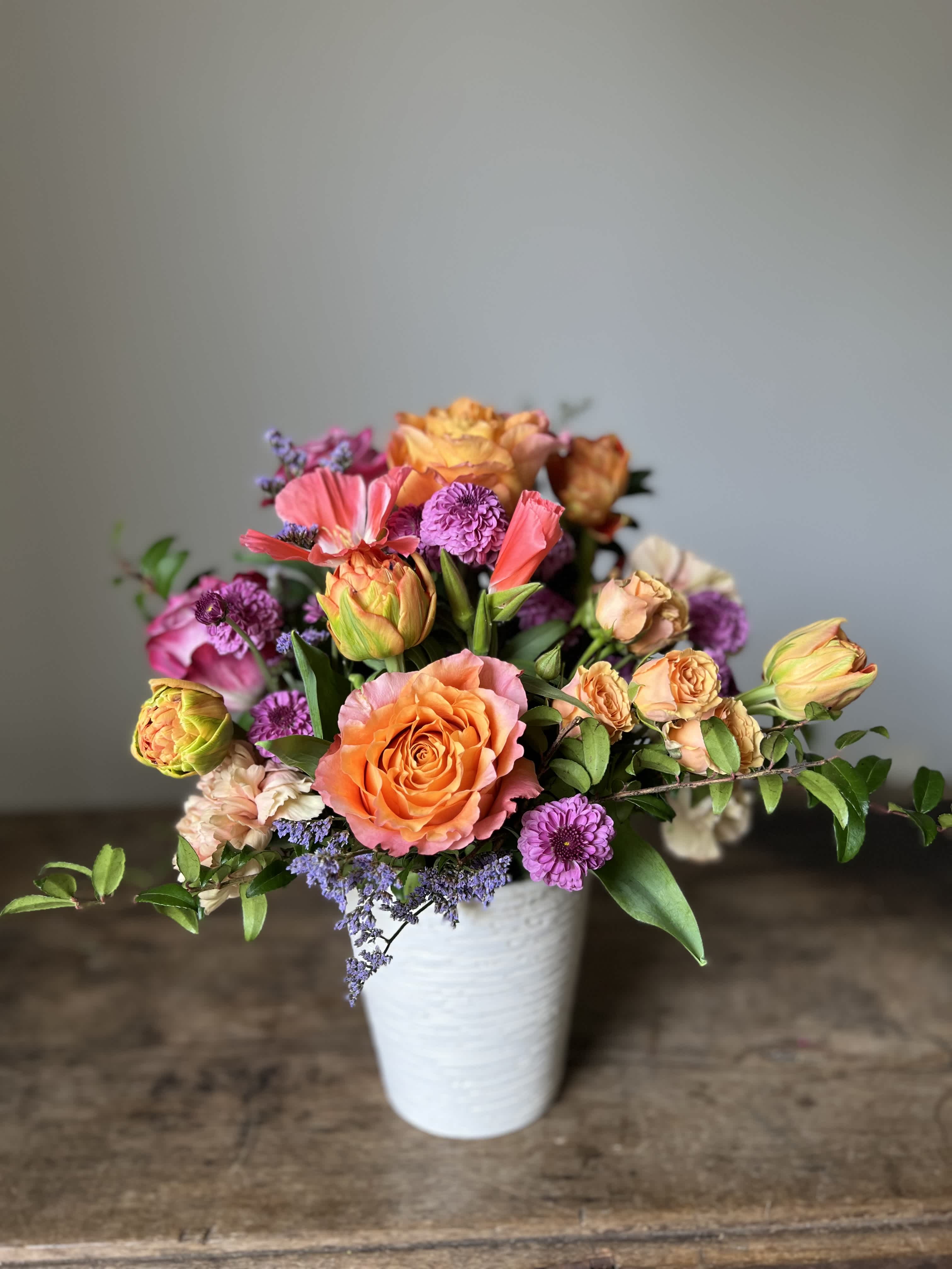 Garden of Delight Garden of Delight - This vibrant floral arrangement is a celebration of seasonal exuberance, featuring a harmonious blend of roses, tulips, and assorted blooms in a ceramic vase. The arrangement bursts with color . Complementing these flowers is a ceramic vase, with its soft glaze and subtle texture, provides the perfect backdrop, allowing the vibrant hues of the flowers to shine.