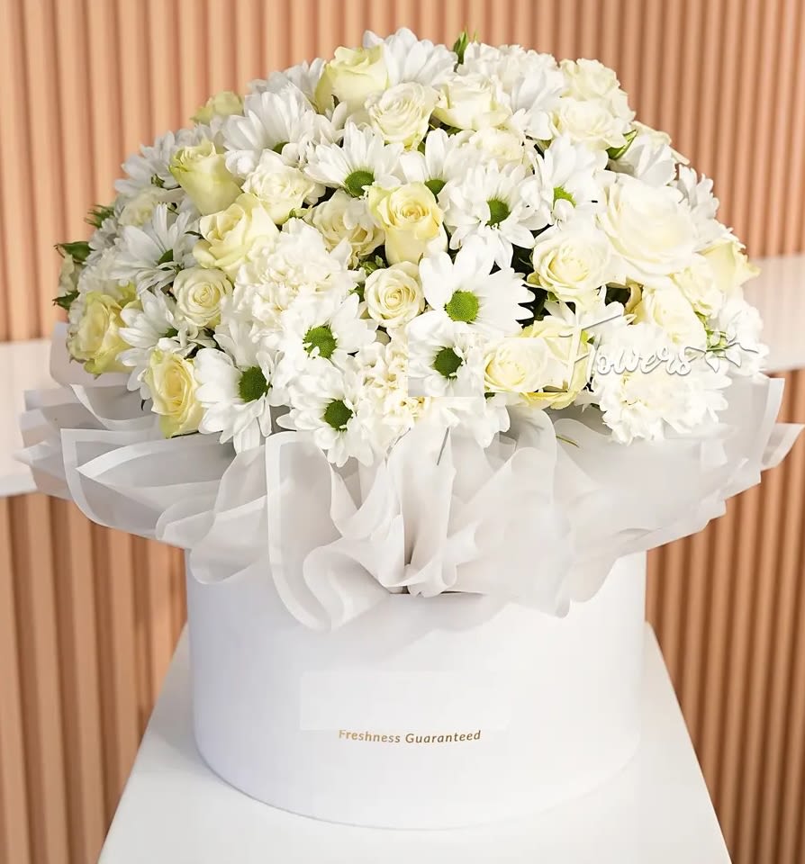 Exquisite Arrangemen Box Exquisite Arrangemen Box - An exquisite arrangement of white roses, white carnations, and white chrysanthemums, beautifully wrapped in white paper and presented in a white round box. Perfect for any occasion. Order now for a timeless touch!