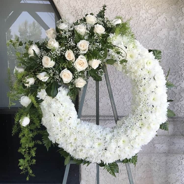White Roses and Lilies Wreath White Roses and Lilies Wreath - Our meticulously crafted White Roses and Lilies Wreath, featuring pure white roses and serene lilies, serves as a touching symbol of sympathy and remembrance. This elegant arrangement offers comfort and solace, making it a heartfelt tribute for honoring your loved one.