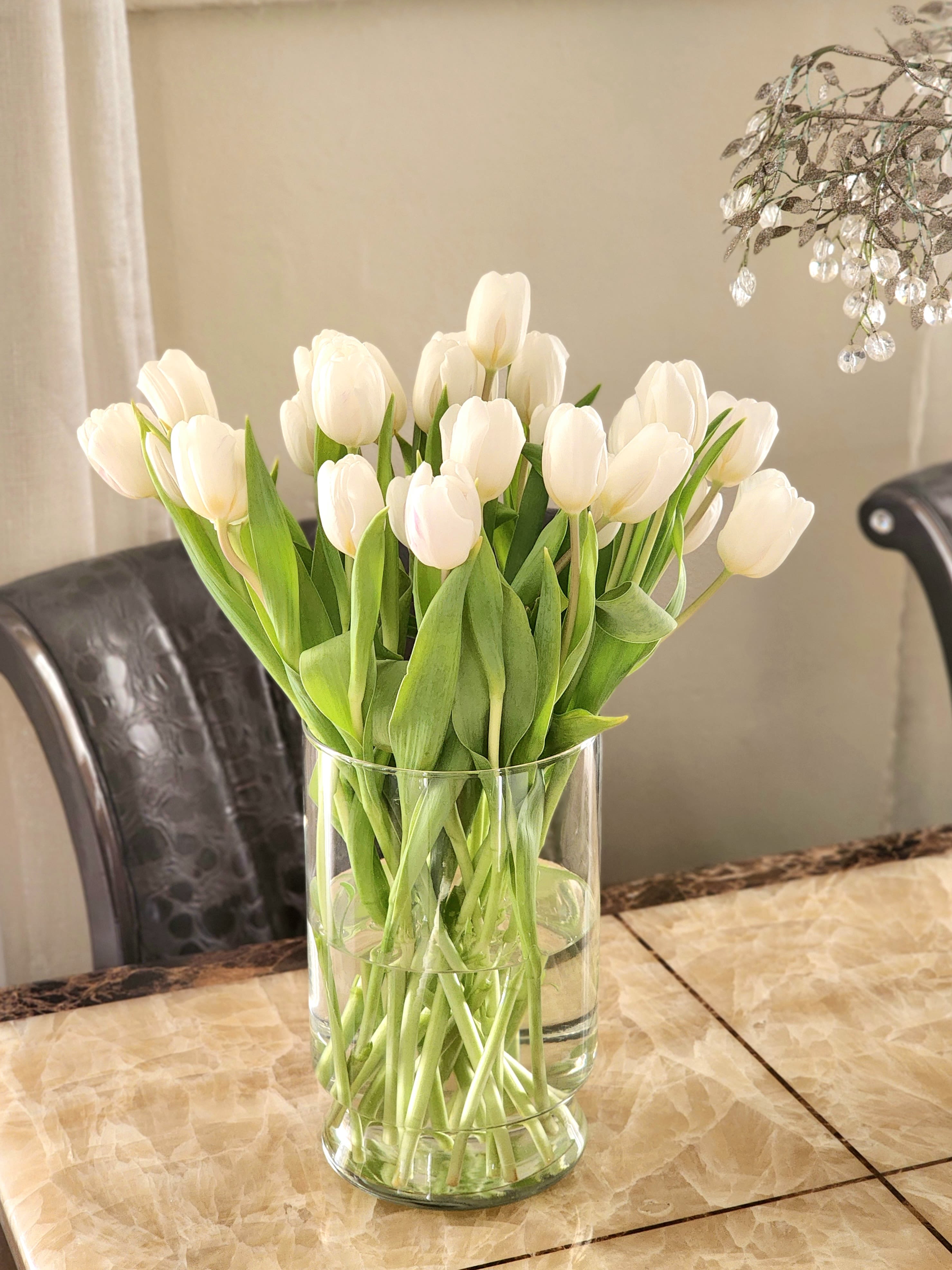 White Tulips  - This arrangement features pure white tulips, artfully designed in a modern glass vase. Perfect for brightening any room, office, or special occasion, this stunning floral piece is a timeless gift