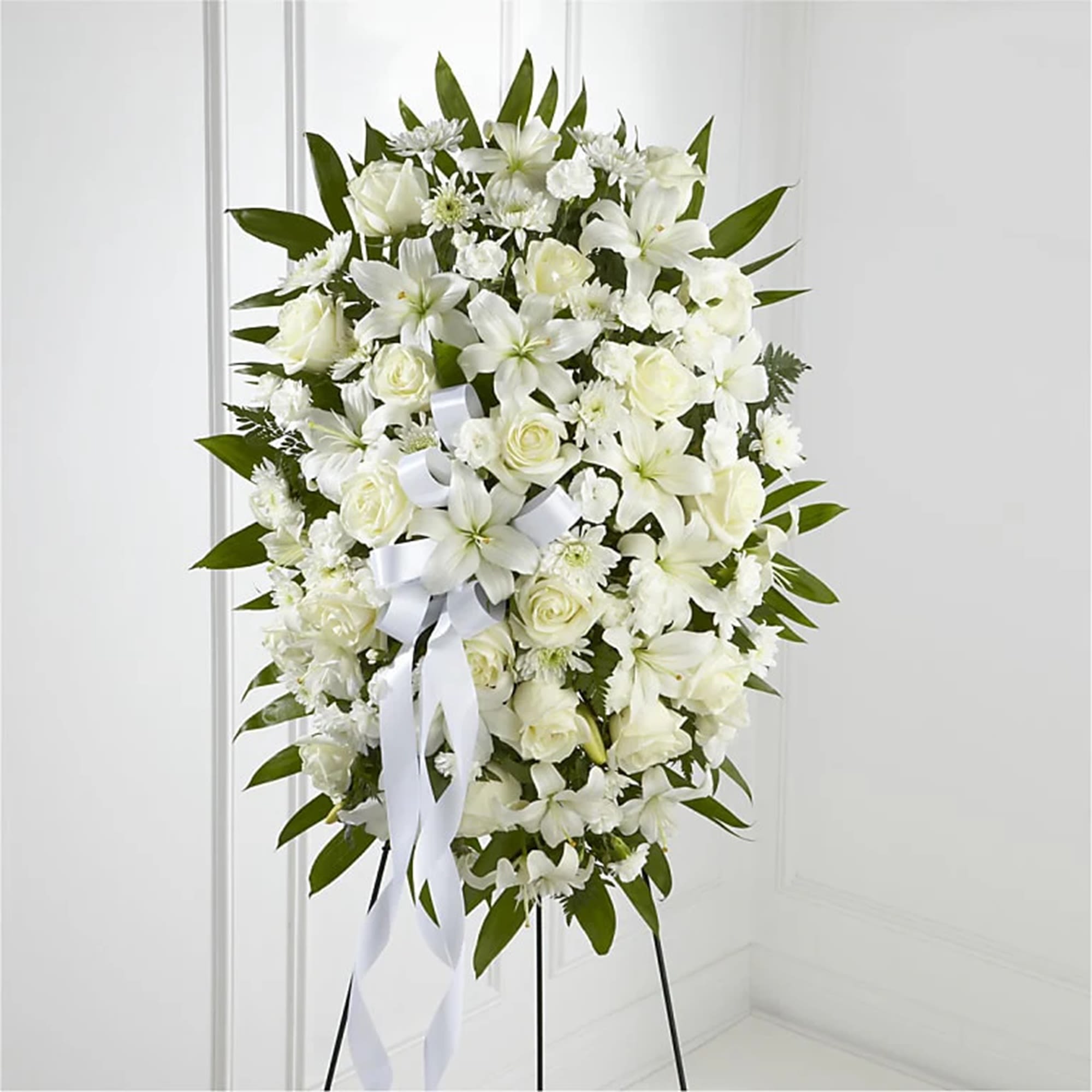 Luxury - Exquisite Tribute Standing Spray - White Ribbon - The Exquisite Tribute Standing Spray is an elegant display of sweet serenity. White roses, Asiatic lilies, chrysanthemums and mini carnations are artfully arranged amongst emerald palm fronds and lush greens. Accented by white satin ribbon and standing on a wire easel, this standing spray is an outstanding way to honor the life of your loved one. What a lovely traditional arrangement meant for celebrating the life of a loved one at a visitation, funeral, church service, cremation, or cemetery service.  DETAILS White roses, Asiatic lilies, cushion-mums, and mini carnations are artfully arranged amongst emerald palm fronds and lush greens.   EASEL INCLUDED Orientation: One-Sided *If you would like to add a ribbon with a sentiment for an additional $10 each. Item #NF-1145  FLORIST-TO-DOOR Same day flower delivery on most orders placed online by 12 pm or 10 am on weekends PST.  BLOOM DETAILS Roses Mini-Carnations Asiatic Lilies Cushion-Mums Greenery  The Standard Arrangement is approx. 34&quot;H x 22&quot;W The Deluxe Arrangement is approx. 35&quot;H x 23&quot;W  The Premium Arrangement is approx. 36&quot;H x 24&quot;W   INSTRUCTIONS: 1.) Please have the business name of the funeral home, address &amp; phone number. 2.) Please have the first name &amp; last name of the deceased. 3.) Please have the start time of the services. 4.) If you would like for us to write a brief message on a small business card-size note, please have your message ready.  NINFA'S FLOWERS 2405 WHITTIER BLVD. LOS ANGELES, CA. 90023