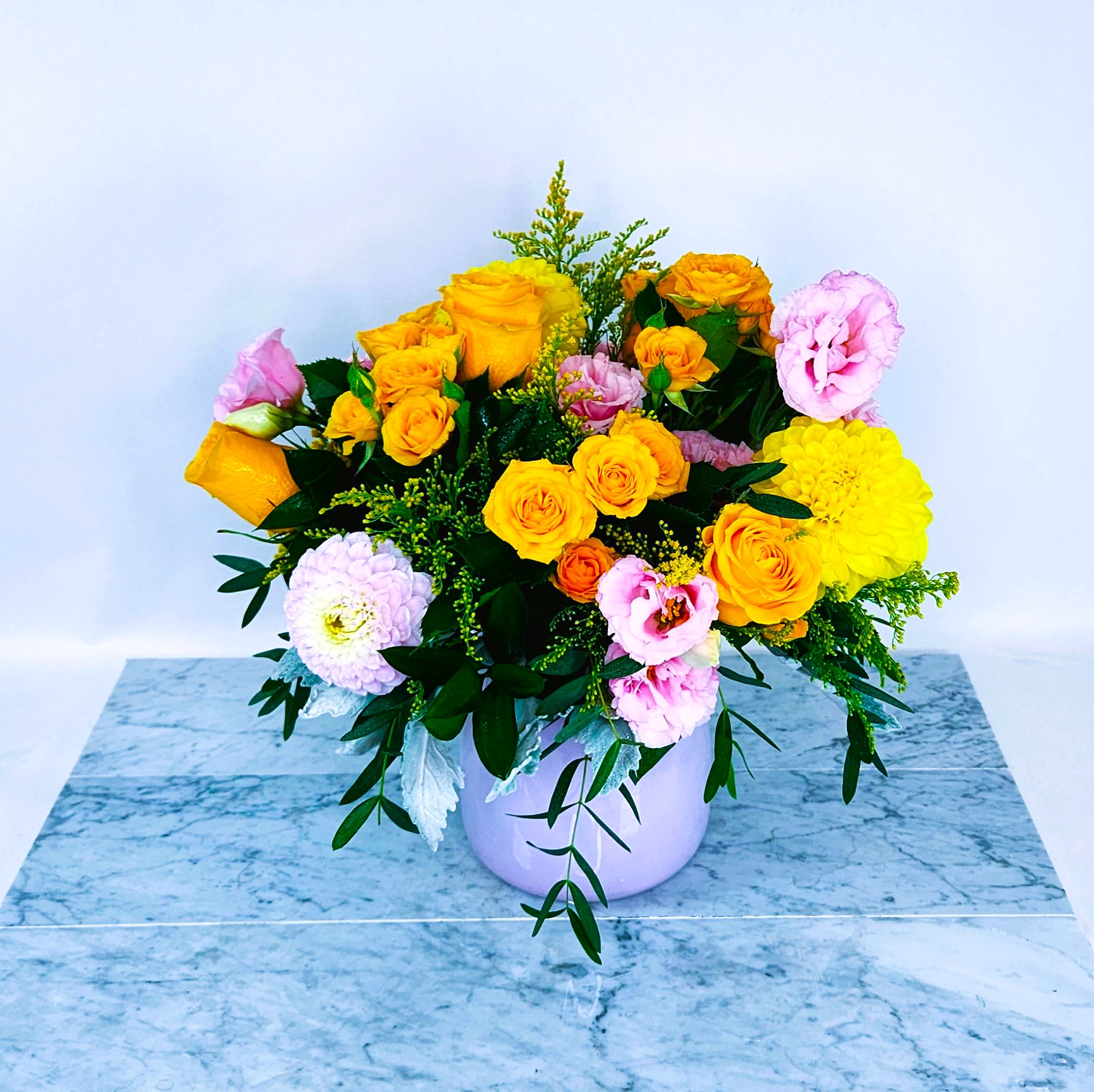 Happy and You Know It - Pink glass vase filled with a beautiful mix of yellow roses, spray roses , Pink Lisianthus, and topped with locally sourced dahlias.