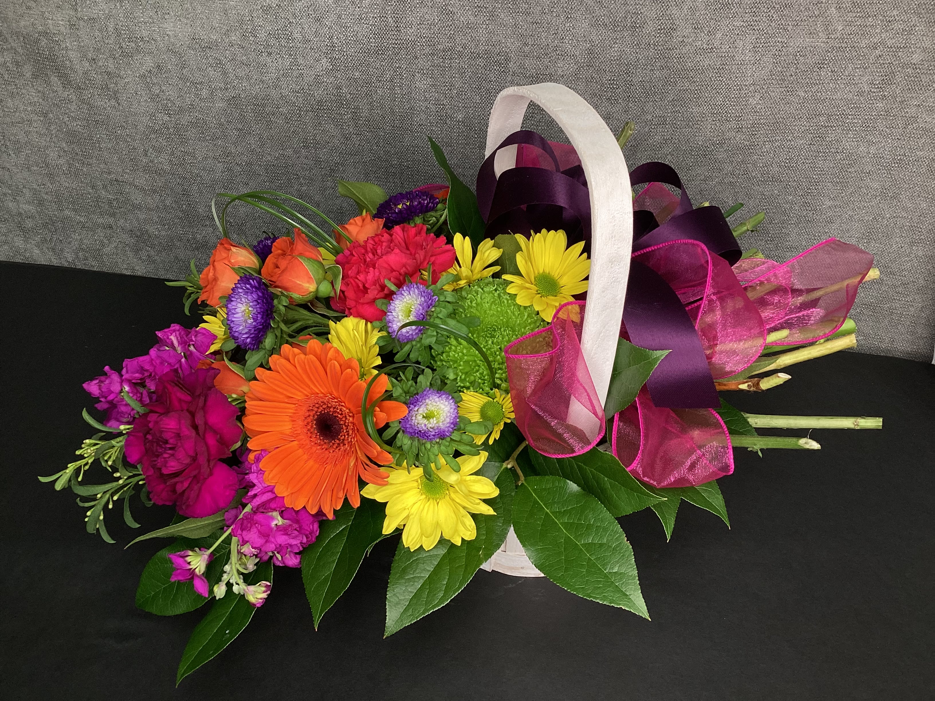 Bountiful Blooms Basket Bountiful Blooms Basket - This unique design makes you feel like you just walked through a meadow and picked them. Bright colors & long-lasting are florals arranged to look like loose stems gracefully laying across the 7" basket with big fluffy ribbons at the open stems.