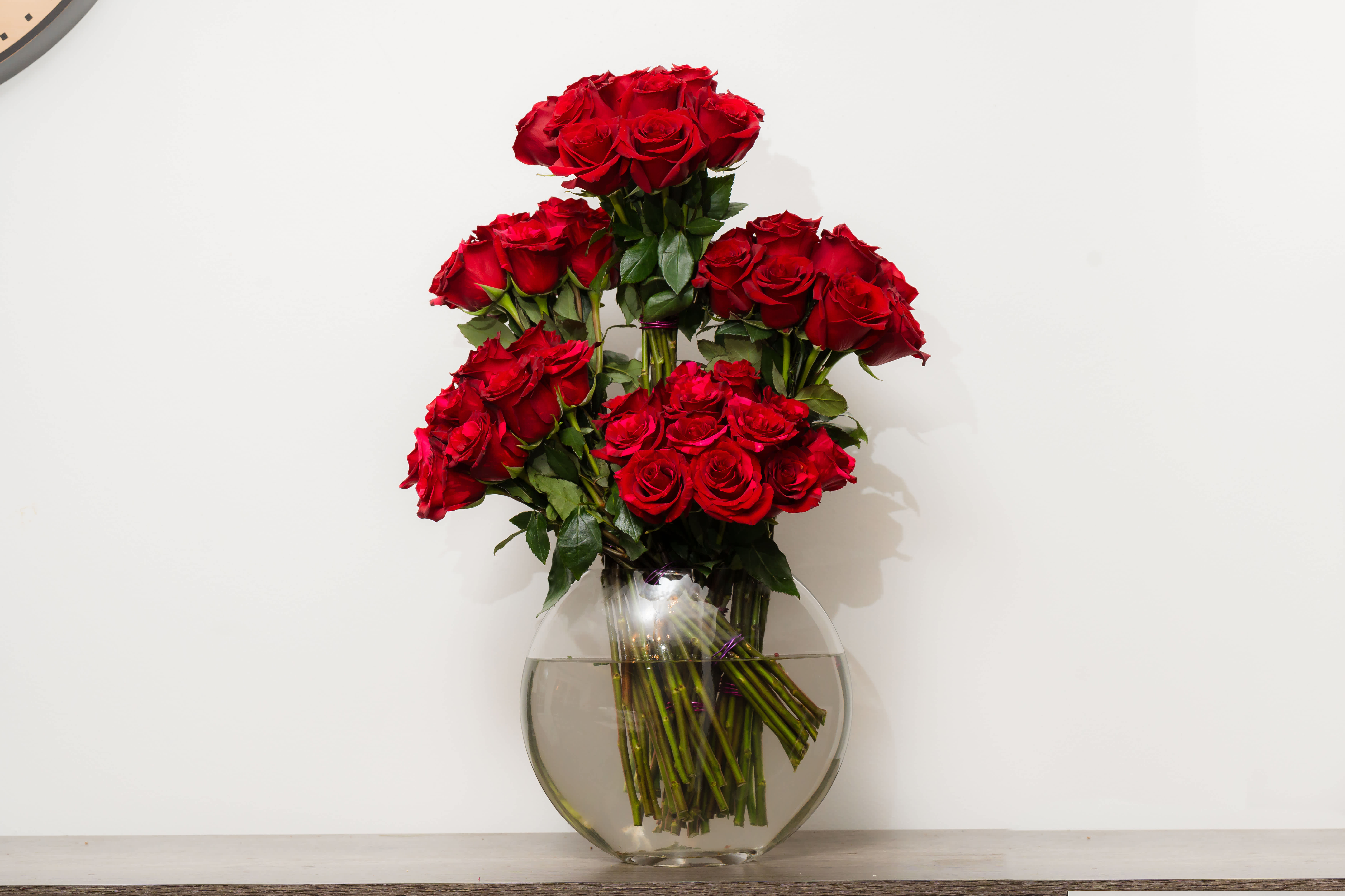 Kalyna - A modern and unique design in a tall glass vase made of 3 dozen roses and luxurious tropical greens and hydrangeas. 
