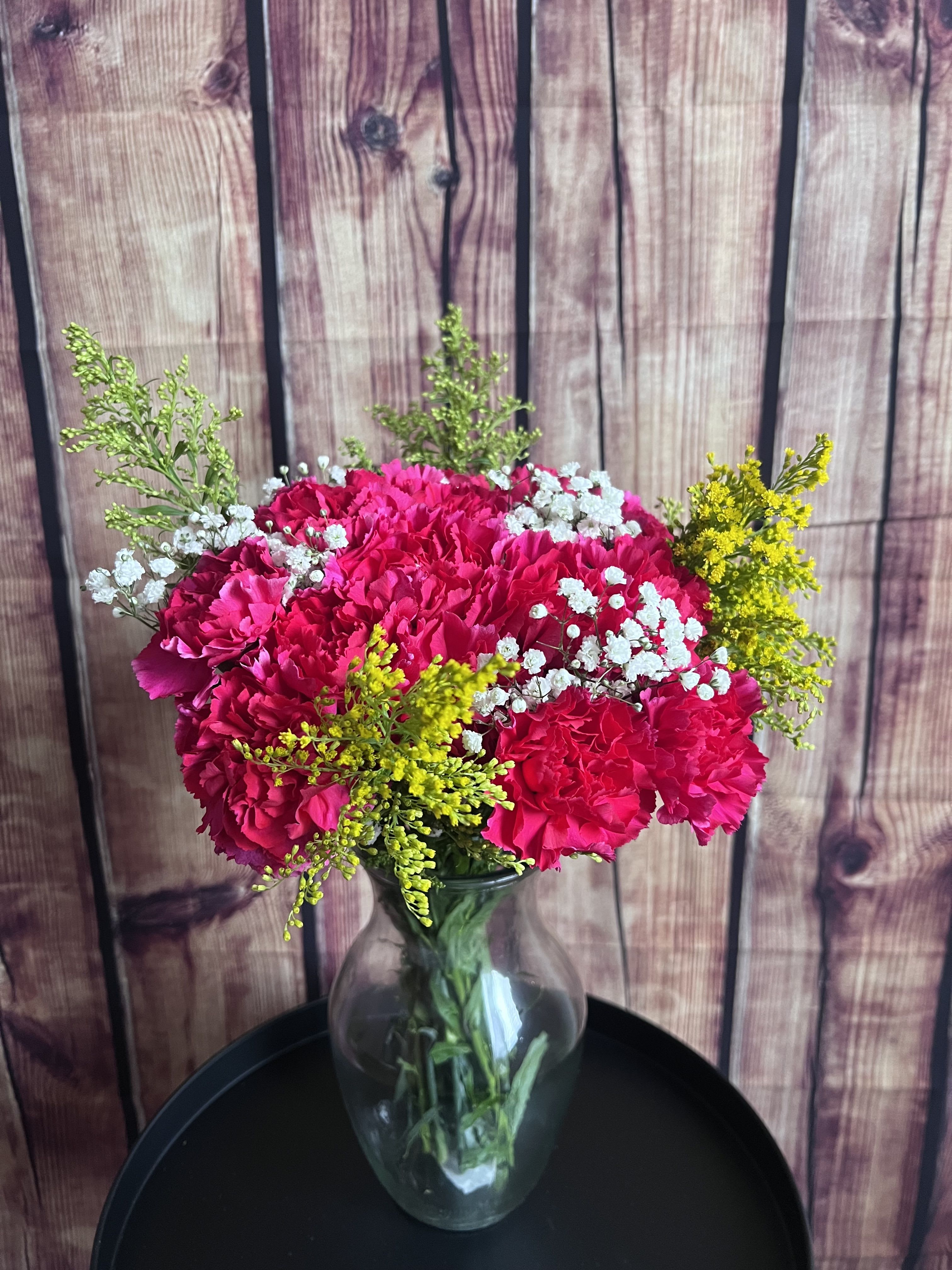 Spring Fling  - A beautiful bouquet of Carnations with a pop of babies breath and filler sitting in a vase. Carnation flower color will vary depending on availability. 