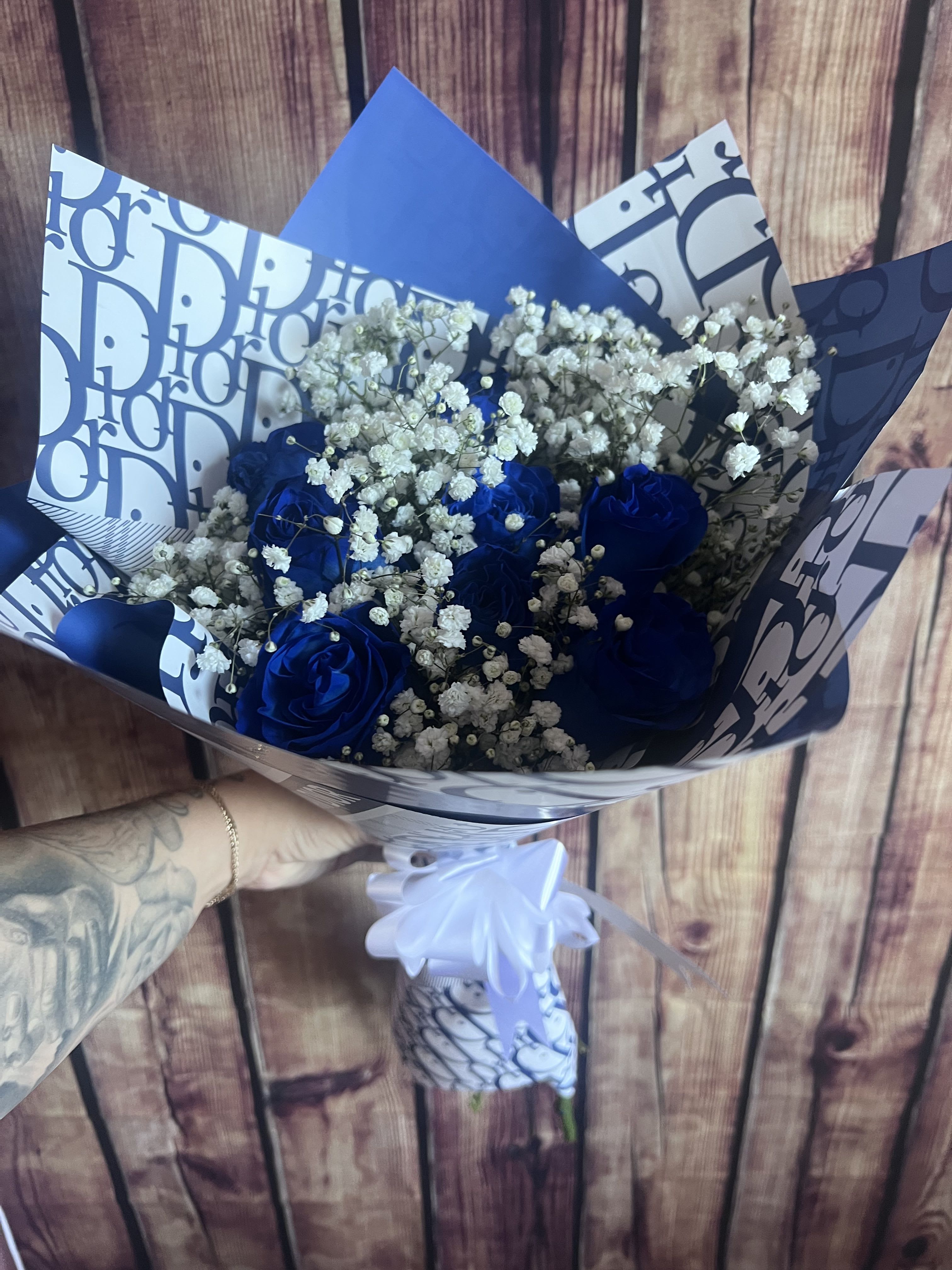 Unique Bouquet - 8 Blue Roses paired with babies breath wrapped in paper and tied with a bow. Paper may vary depending on availability. 