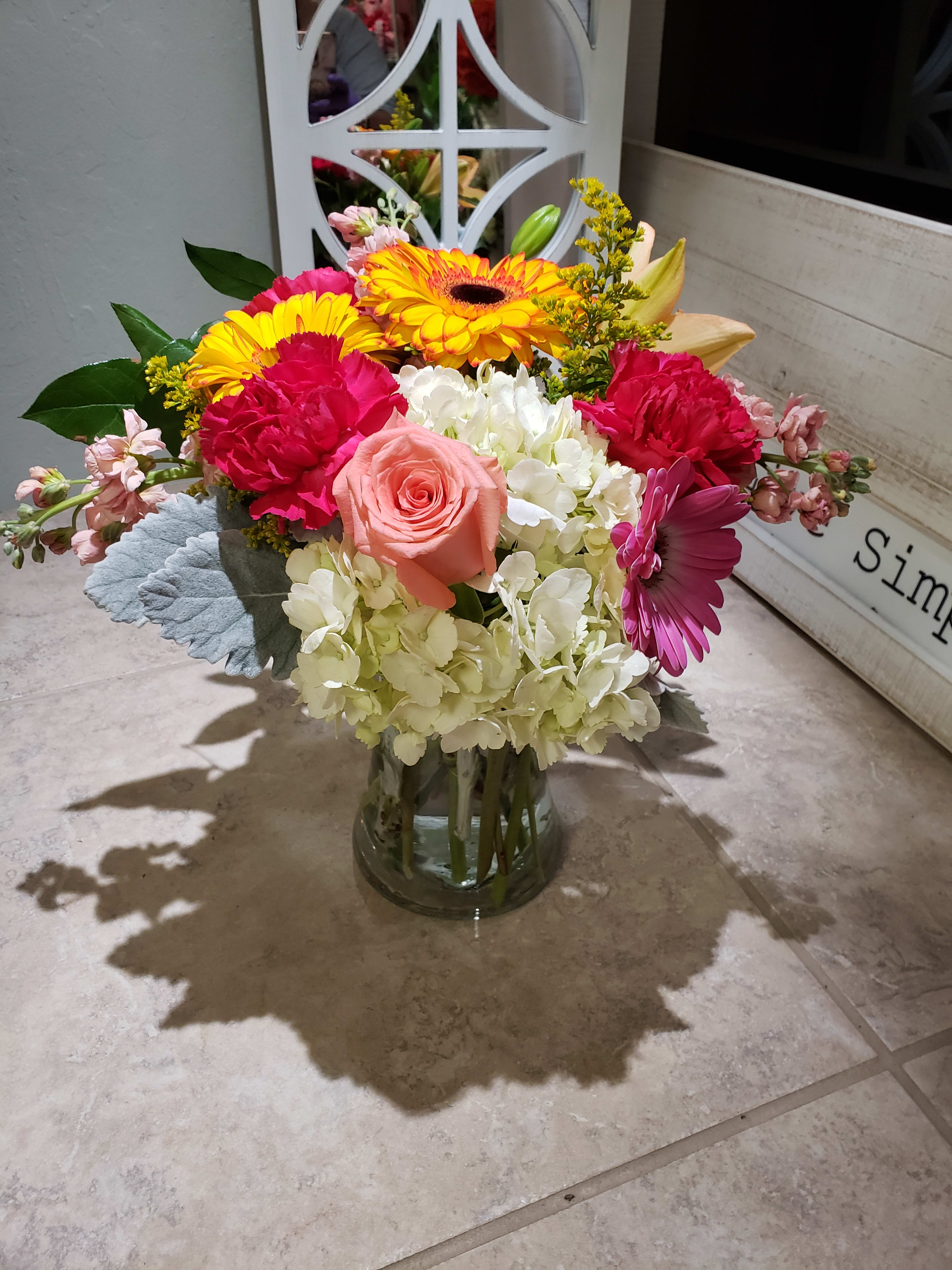 Alexandria's Seasonal Vase Arrangement Alexandria's Seasonal Vase Arrangement - In-season flowers in the spring include roses, gerberas, stock, spray roses, sunflowers. A bright mix designed in a clear vase. Picture is deluxe size.