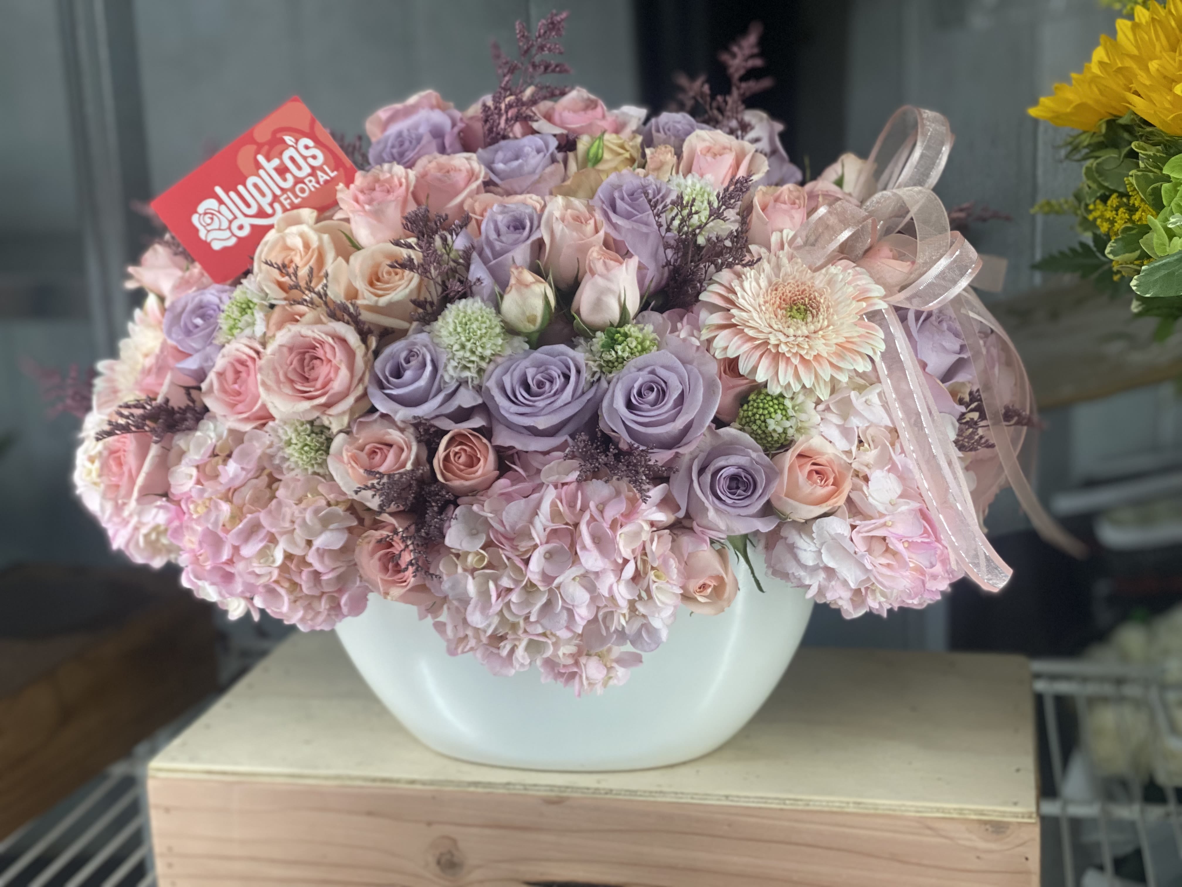 Pure Angelas Pure Angelas - Focal Flower will be Mini Roses, Hydrangeas & Roses. You may request change in colors during checkout. Vase Length 11.5inches. Vase Width 4.75”.