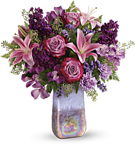 Amethyst Jewel Bouquet - A jewel of a gift! Bursting with a lush bouquet of lavender roses and pink lilies, this breathtaking, hand-blown art glass vase has a shimmering iridescent finish and soothing amethyst hue that's sure to make it a home décor favorite! This bouquet features lavender roses, pink asiatic lilies, purple alstroemeria, lavender carnations, lavender sinuata statice, seeded eucalyptus, and leatherleaf fern. Delivered in an Amethyst Gemstone Art Glass vase. Approximately 18 1/2&quot; W x 20 1/2&quot; H 