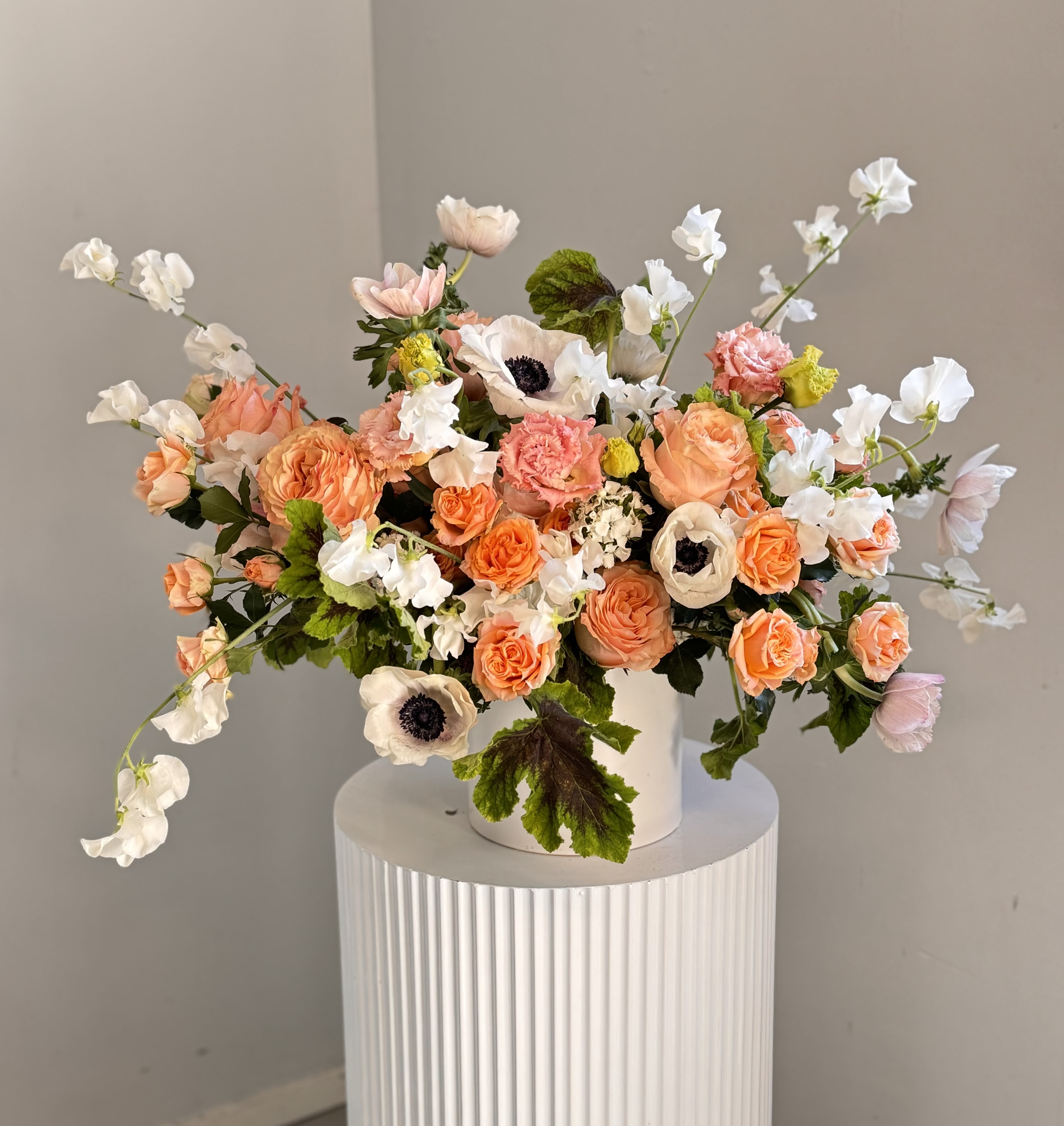 Delicate Affection Delicate Affection - Delicate Affection - Delicate, romantic, and full of charm, this exquisite arrangement combines the soft elegance of peach roses, the striking beauty of white anemones, and the sweet fragrance of tender sweet peas.
