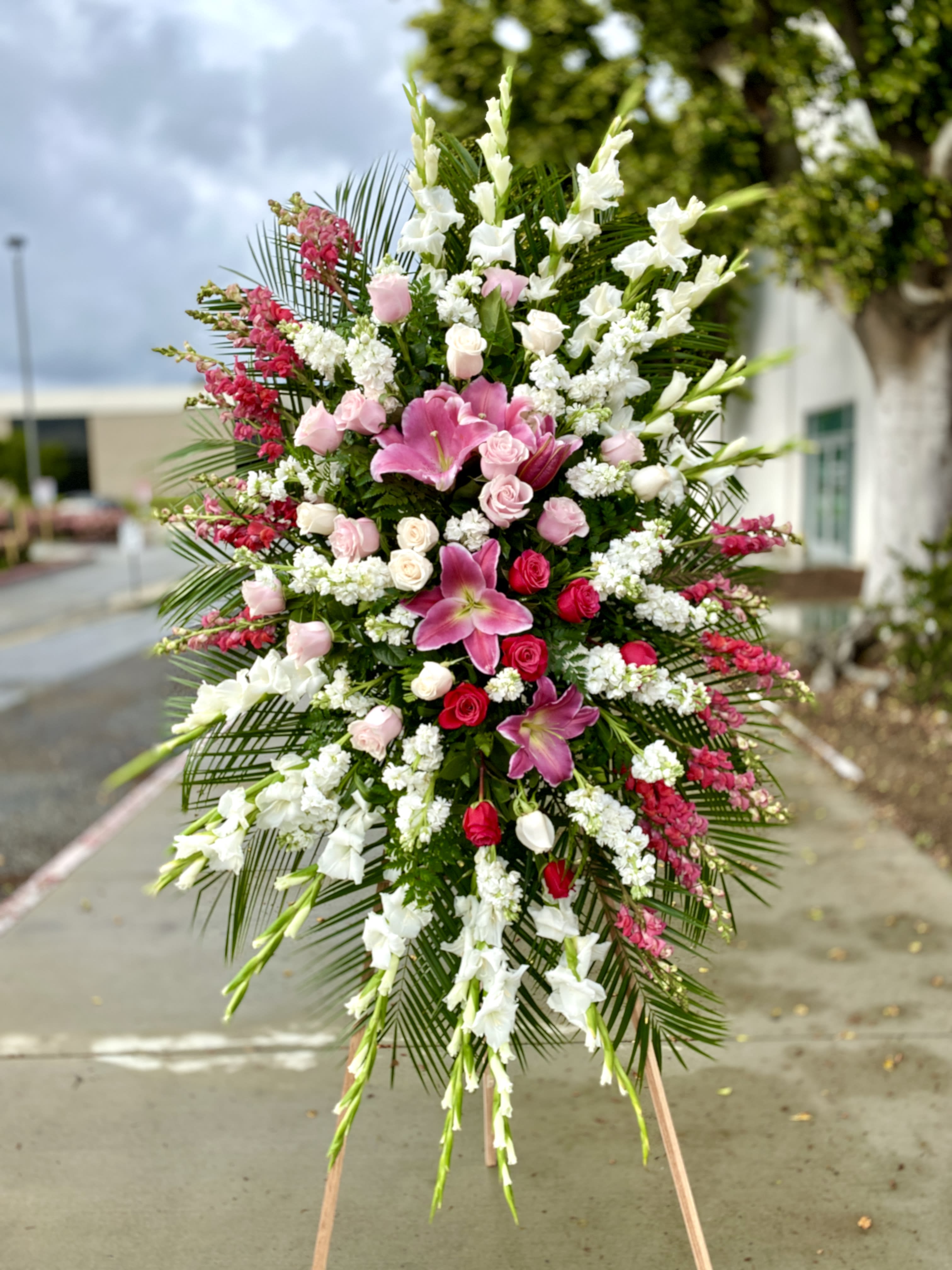 Pink and White Sympathy Spray - Lilies, Glads, Roses - Our lush Pink and White mix is a favorite at our store. Made up of an assortment of Roses, Stock flowers, Gladiolus, Ti Leaves, Stargazer Lilies and other mixed flowers on a bed of green and fillers. In total the height of the arrangement when on display is about 9ft. We can customize the colors/flowers according to desire and availability. (This photo is property of Andes' Florist, this is an example of an arrangement Andes' Florist has made and delivered.)