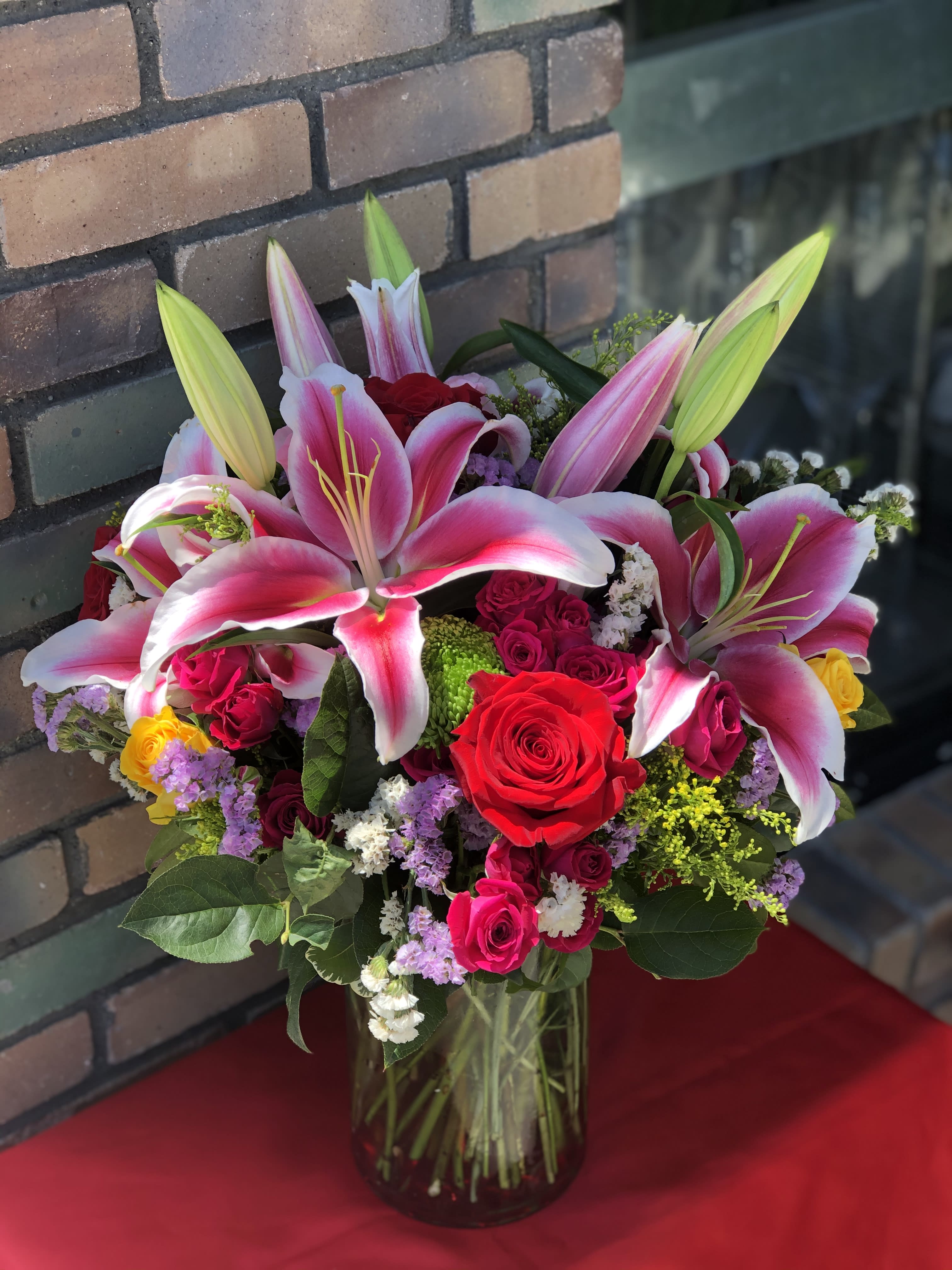 Garden Where Love Grows - A lovely assortment of lilies, roses, spray roses, and a handful of different type of fillers and unique flowers in a tall vase