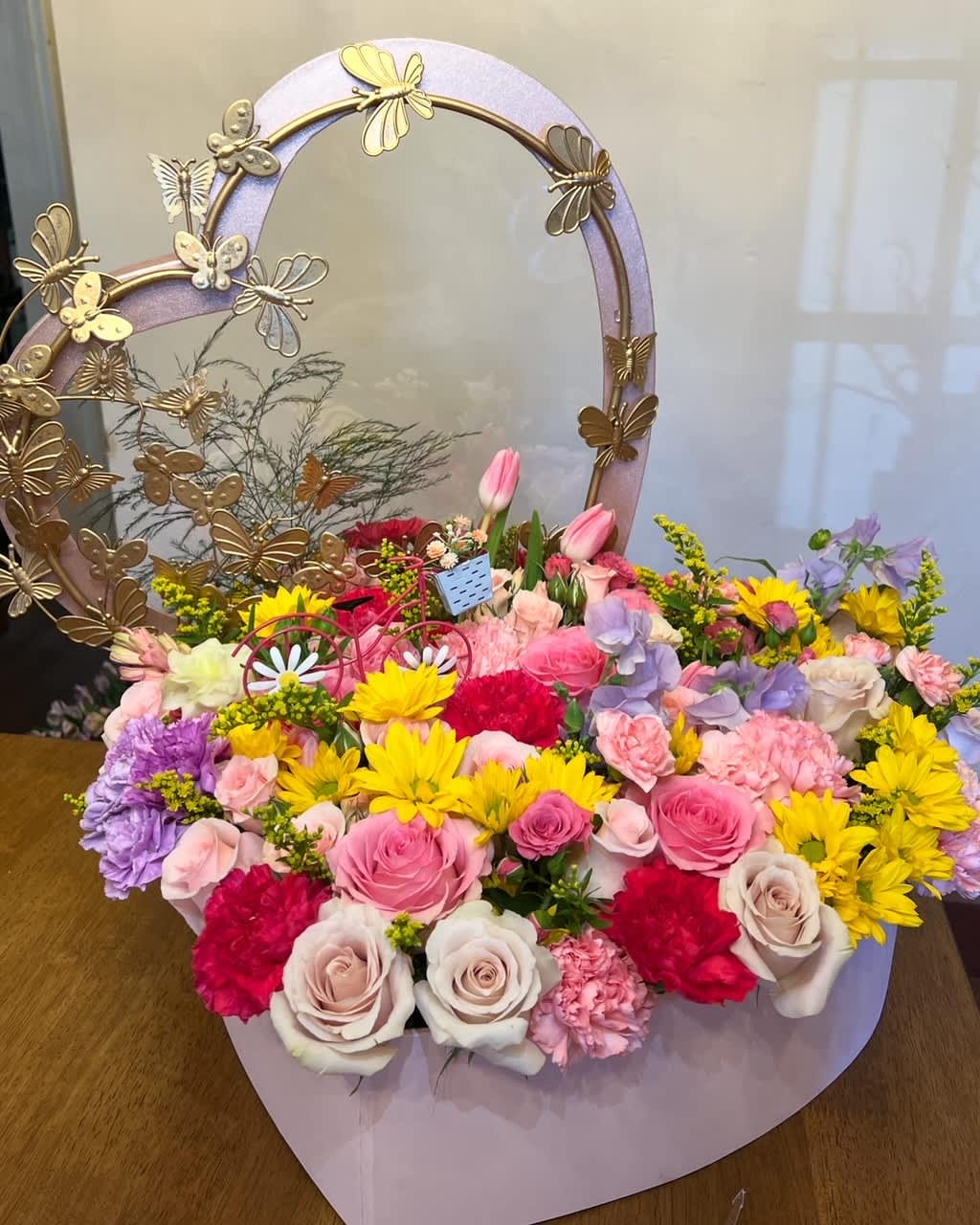 Chasing butterflies - Large heart box with metal butterfly frame.  Spring flowers: roses, carnation, alstromerias, daisy, tulip in pink, yellow, and lavender. 