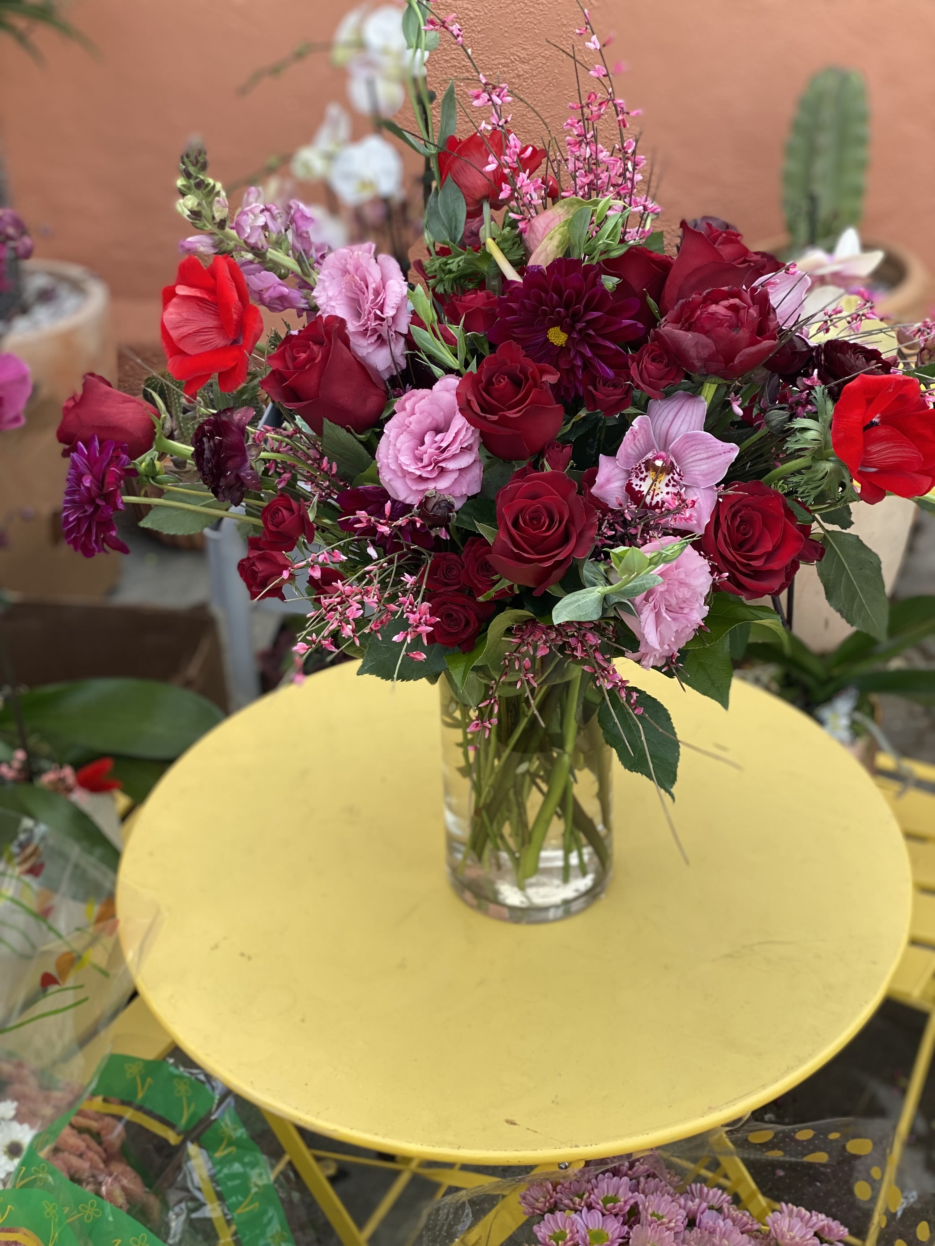 JoAnie  - An elegant arrangement in a glass vase, with  roses, cymbidium, snap dragons and much more.  A perfect gift for an Anniversary present. 