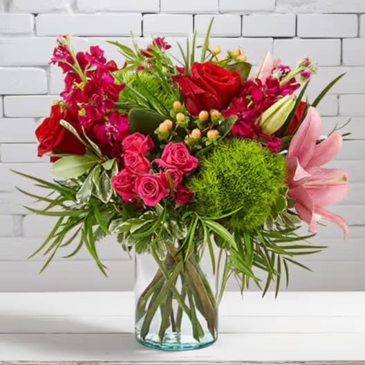 Truly Stunning - Our Truly Stunning Bouquet instantly complements any room with luscious blooms and bold colors. Featuring truly elegant blooms like red roses, pink lilies, green dianthus, and more set in a clear glass cylinder vase, this collection of flowers livens up wherever its placed. Great to send to your special someone for a birthday, wedding anniversary, get well wishes, or just a reminder of just how much you care.  Regular bouquet is approx. 14″H x 15″W.  Care Instructions for Fresh Flowers: Check water level upon arrival, and add very cold water if needed. Keep any arranging foam saturated, and vases very full of water. Keep cut flowers out of direct sunlight and avoid excessively hot or cold areas. Place a tray under flowers and plants to protect decorative surfaces.   Available for delivery to East Moline, Moline, Rock Island, Silvis, Colona, Hampton, Coal Valley, Milan, Davenport, and Bettendorf. 