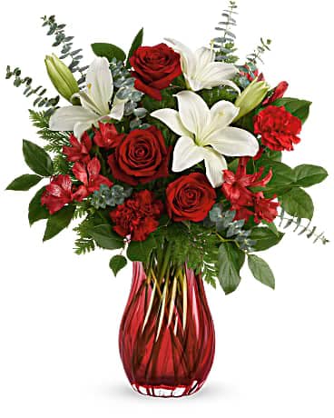 Love Conquers All Love Conquers All - Give Valentine's Day a dramatic twist with this romantic, swirling glass vase. Its ruby red ombre hue is the perfect complement for ravishing red roses and snow white lilies. Red roses, white asiatic lilies, red alstroemeria and red carnations are arranged with spiral eucalyptus, leatherleaf fern and lemon leaf. Orientation: All-Around All prices in USD ($) Due to an increase in the cost of roses, some product prices may be impacted during the Valentine’s delivery period.