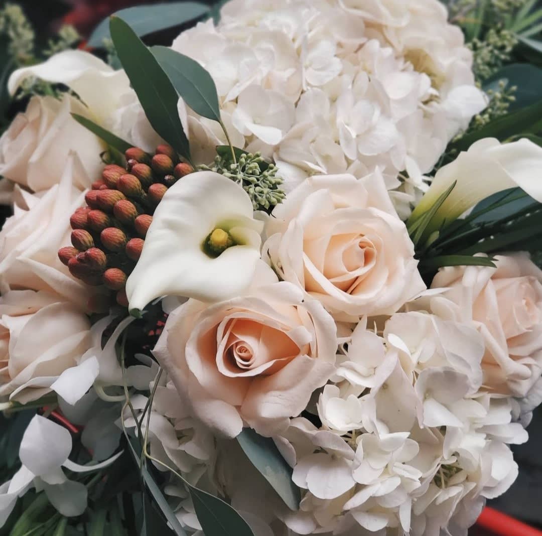 Winter whites Winter whites - A magic white blooms of hyadrangea and mini callas and roses, finished with seasonal greenery in a cylinder clear vase.