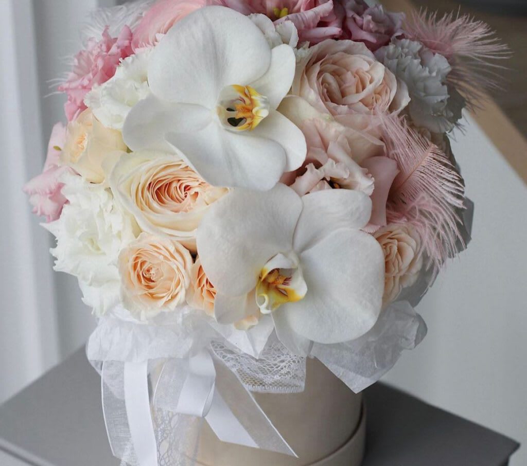 Elegant Peonies &amp; Orchids Whisper Box - The &quot;Elegant Peonies &amp; Orchids Whisper Box&quot; is a stunning floral arrangement that embodies sophistication and gentle beauty. Featuring a luxurious blend of soft peach roses and delicate white peonies, this arrangement is beautifully accented with pristine white orchids and soft pink lisianthus. Presented in our signature hat box and adorned with a delicate ribbon, this arrangement is perfect for any special occasion or to simply add a touch of elegance to your space.  Arrangement Details: Main Flowers: Peach roses, white peonies, white orchids Accents: Pink lisianthus Container: Be Bloom's signature hat box with a delicate ribbon Approximate Dimensions: 14&quot;D x 18&quot;H