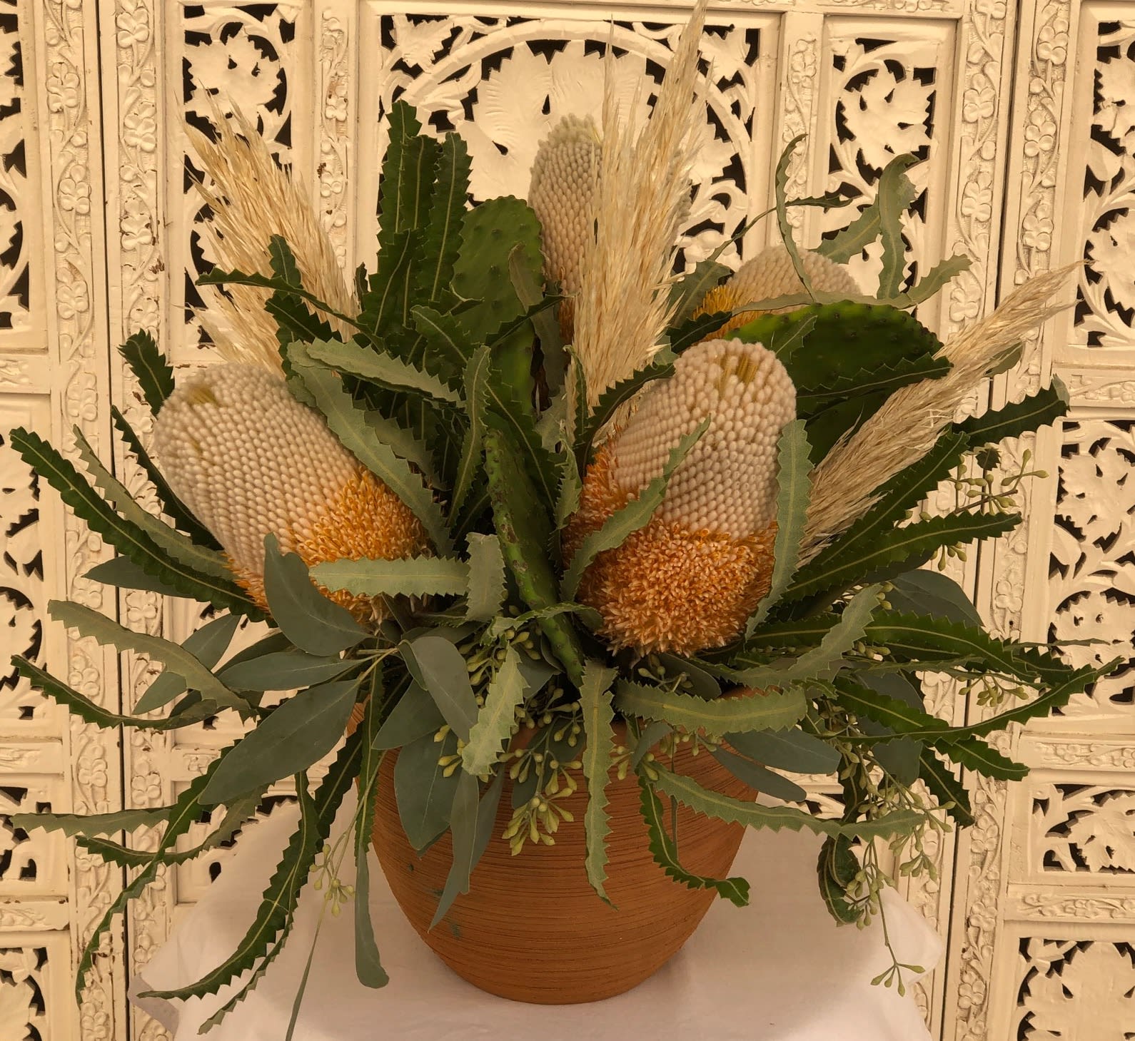 Cabo San Lucas Centerpiece - A very unique collection of Banksia Flower, Pampas Grass and Nopales Cactus designed together in terracotta and accented with textures of Seeded Eucalyptus and bay..  An Urth Gardens Original!