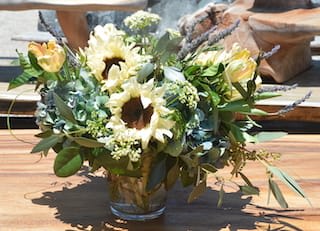 Buddha's Sunflowers - Earthy pastel toned arrangement with a lot of texture.  Features antique hydrangea, sunflowers and tulips in a glass vase with stems bundled in curly willow.  Perfect arrangement for summer or fall.  Great compliment to any table or occasion.