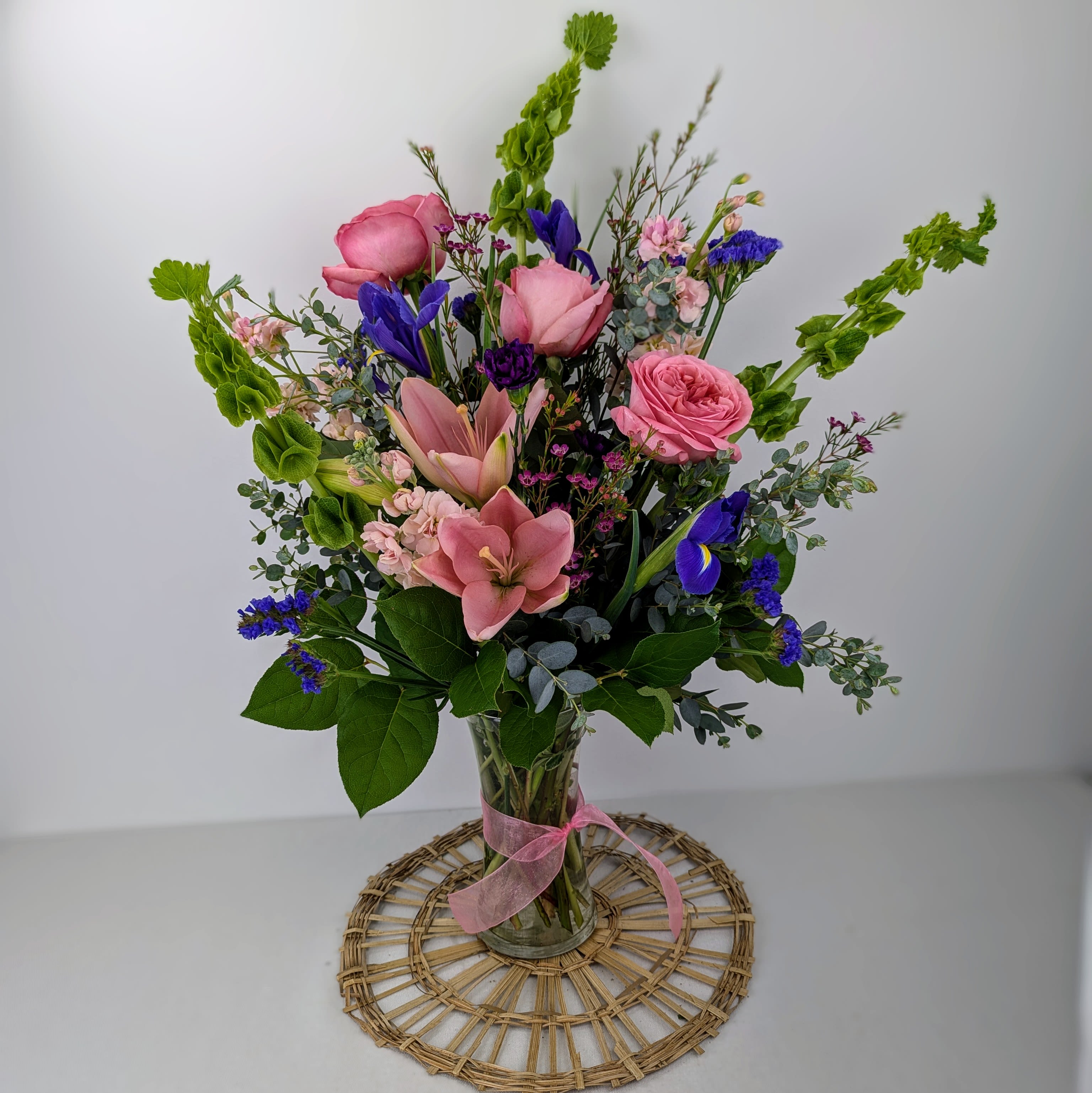 Enchanted Fairytale - This arrangement contains pink lilies, bells of Ireland, stock, blue iris, pink roses, carnations, and filler flowers. This is a great gift for birthday, Mother's Day, love and romance, or to say thank you. 