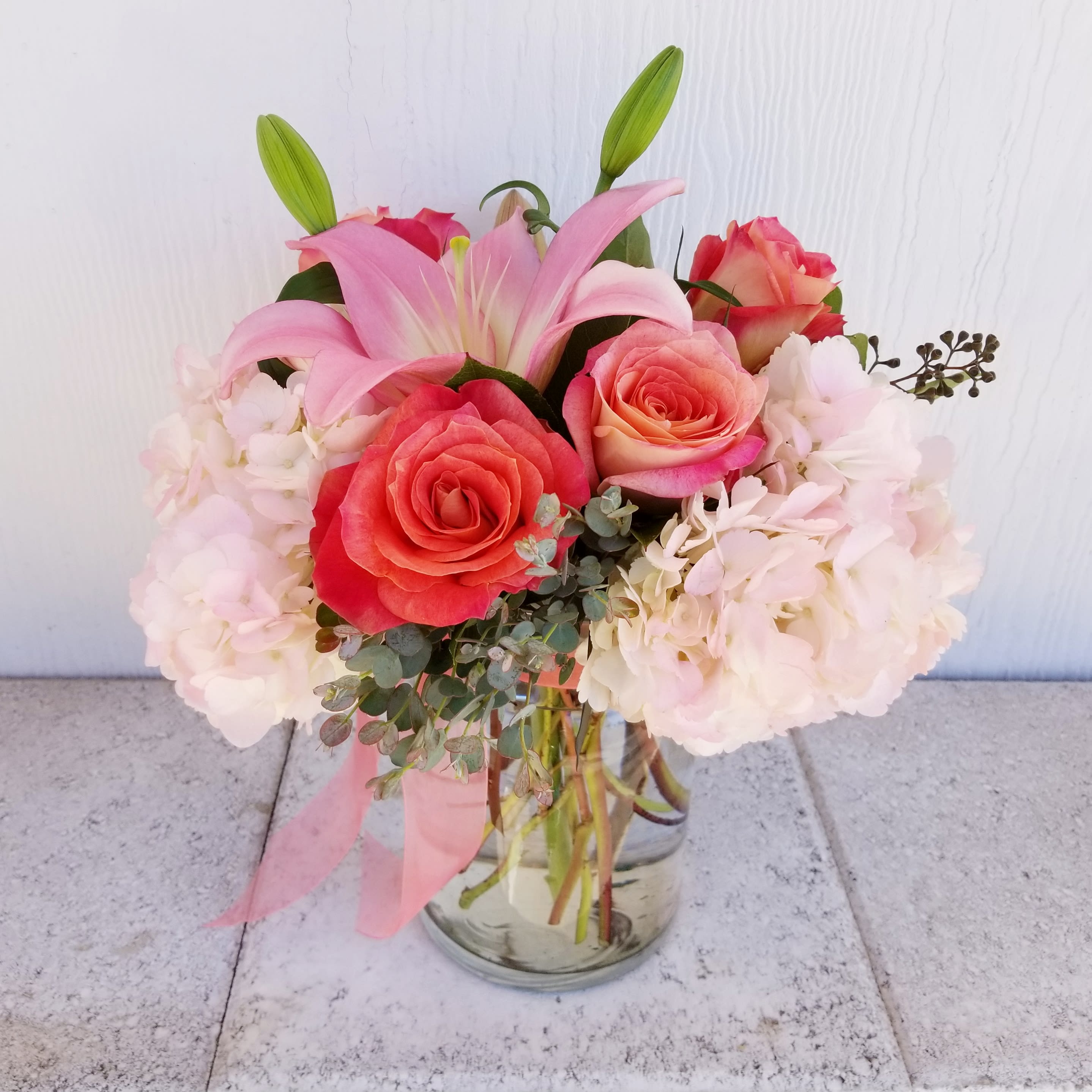 Coral Beauty  - Charming coral and pink in a compact round design.  Beautiful full roses in a fragrant and vibrant, yet soft collaboration.   Deluxe and premium is more flowers in a larger design and vase.