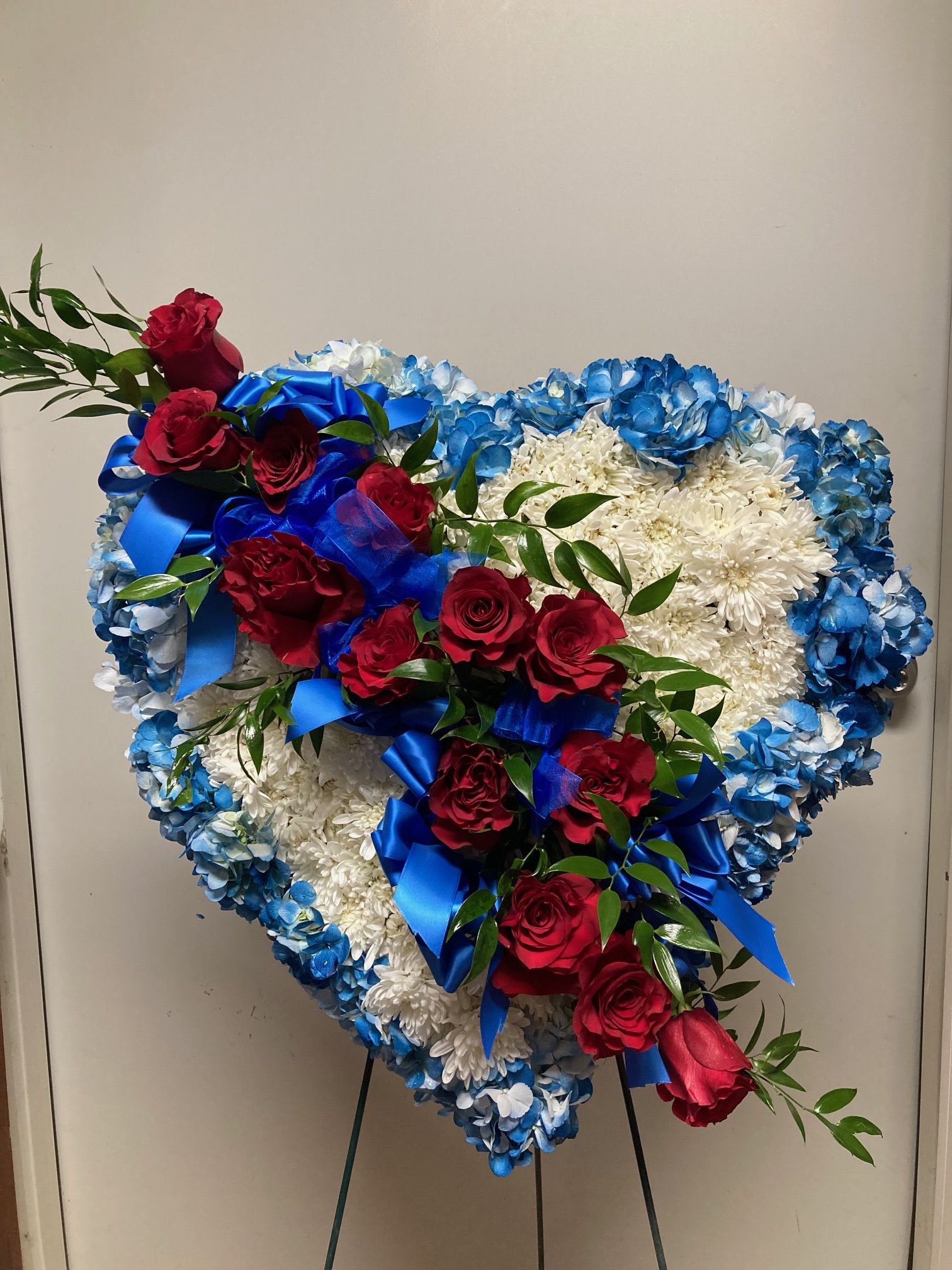 Blue Heart Wreath Blue Heart Wreath - 12 red roses across a field of white poms trimmed in blue hydrangeas