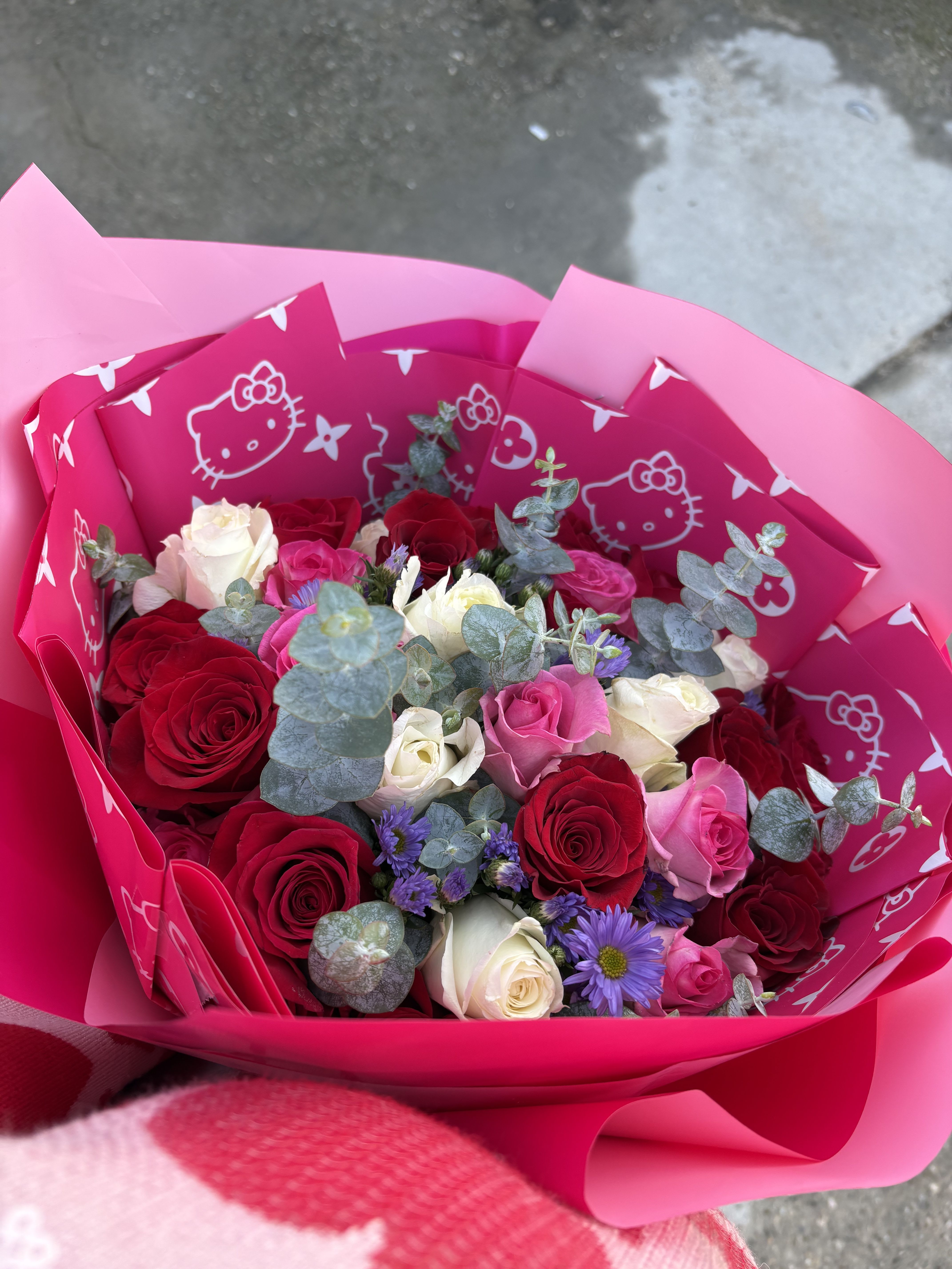 pretty pink pretty pink - a combination of red white and pink roses totaling 24, mixed with eucalyptus and filler flowers wrapped in pretty pink wrapping paper, it could be hello kitty or just plain pink.