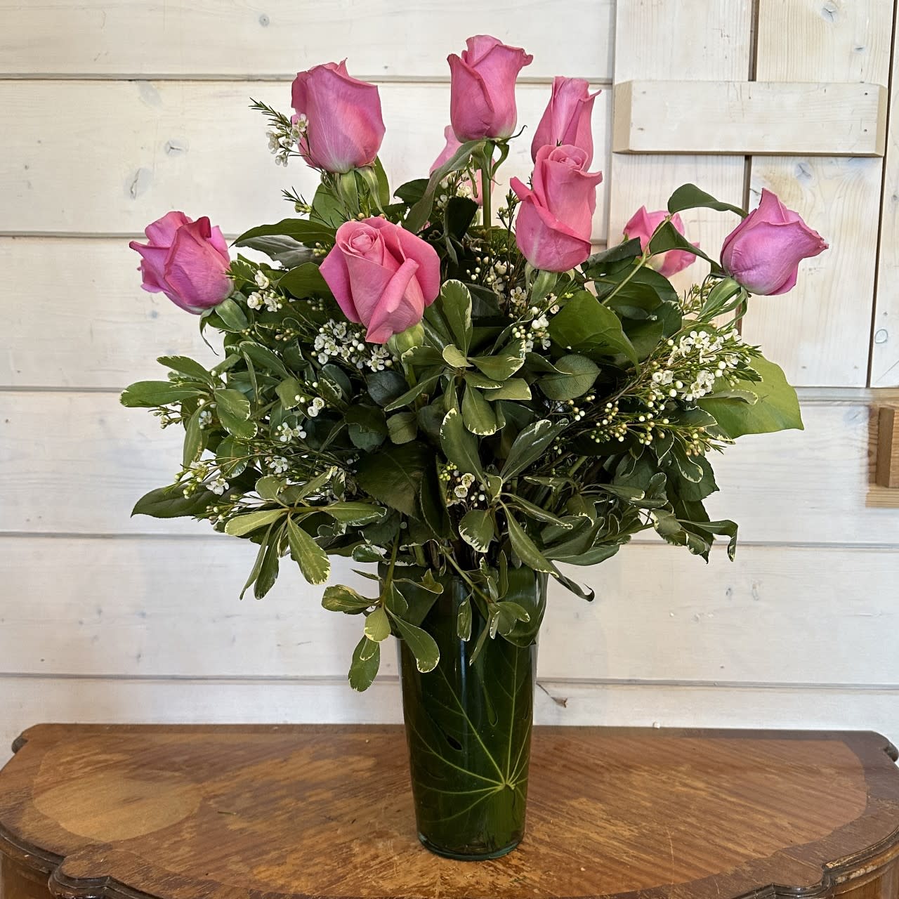 The  Pink Rose Bouquet - Picture-perfect soft pink roses make a beautiful gift for the lovely lady in your life. Wife mother daughter or sweetheart she's sure to cherish this bouquet of pastel pink roses accented with premium greens and complimenting filler flower and arranged in a leaf lined  glass vase. Regular is Dozen roses, deluxe is 18 roses and premium is 2 dozen roses