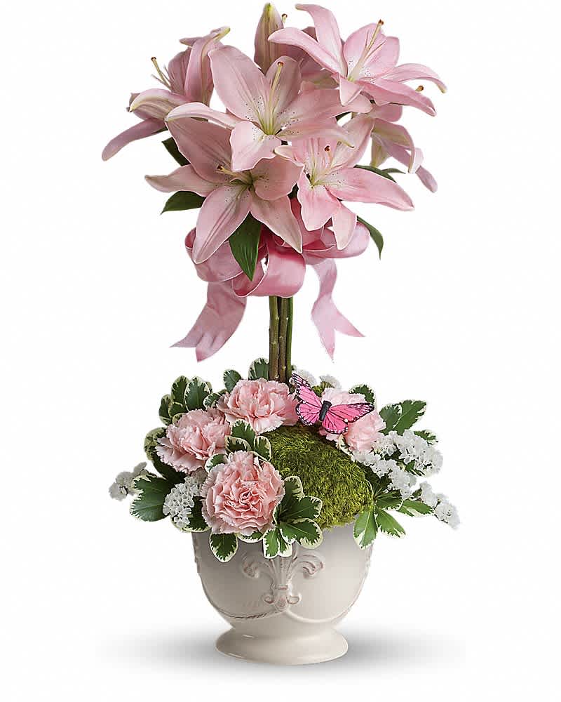 Teleflora&#039;s Blushing Lilies - Like springtime in Paris, this flirtatious topiary makes romance bloom! She&#039;ll adore the pale pink lilies, a pretty pink ribbon, and charming french country pot as well as the loving sentiment that comes with it! Pink asiatic lilies are arranged into a topiary bouquet surrounded by a base of light pink carnations, variegated pittosporum and white statice. Delivered in a large French Country Pot.