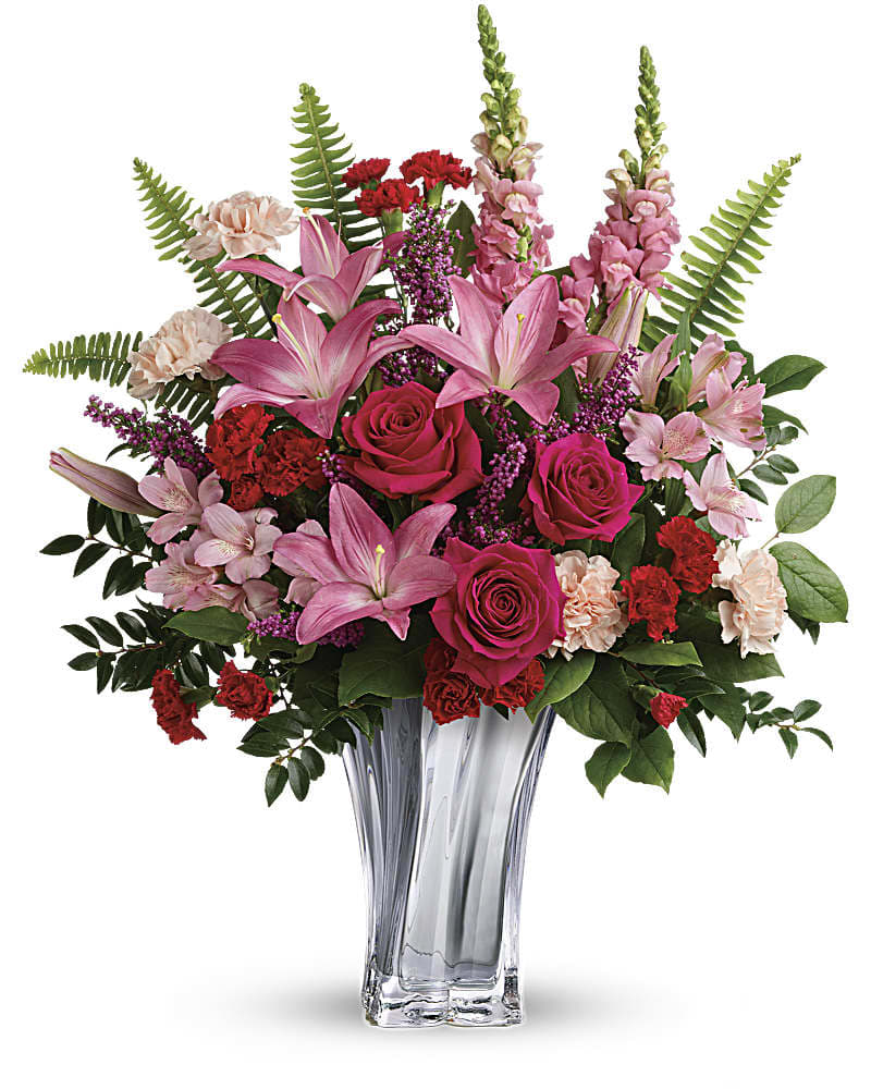 Teleflora&#039;s Elegant Adoration Bouquet - At once elegant and romantic, this breathtaking red and pink bouquet features luxurious blooms and an equally luxurious vase of blown, sterling silver mirrored glass with sleek swirling lines. This elegant bouquet includes hot pink roses, pink asiatic lilies, light pink alstroemeria, peach carnations, red miniature carnations, pink snapdragons, pink heather, sword fern, huckleberry, and lemon leaf. Delivered in a Sterling Love Vase.