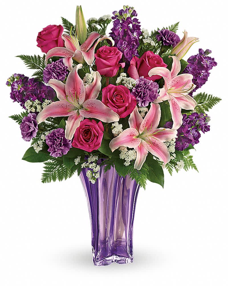 Teleflora's Luxurious Lavender Bouquet Teleflora's Luxurious Lavender Bouquet - The essence of luxury! This dramatic bouquet spoils her with a decadent array of luxe lilies and resplendent roses, hand-delivered in a stunning blown glass vase that's a grand gift in and of itself. Fabulous! This arrangement includes pink roses, pink oriental lilies, purple carnations, white sinuata statice, leatherleaf fern, and lemon leaf. Delivered in a Luxurious Lavender vase.
