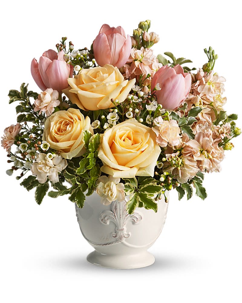 Teleflora&#039;s Peaches and Dreams - The only thing sweeter than peaches and cream just might be this dreamy bouquet of delicious roses and tulips. Be a peach and send one today! Pretty in peach roses, tulips, miniature carnations and stock along with white waxflower and fresh spring greens are beautifully arranged in a ceramic French country container.