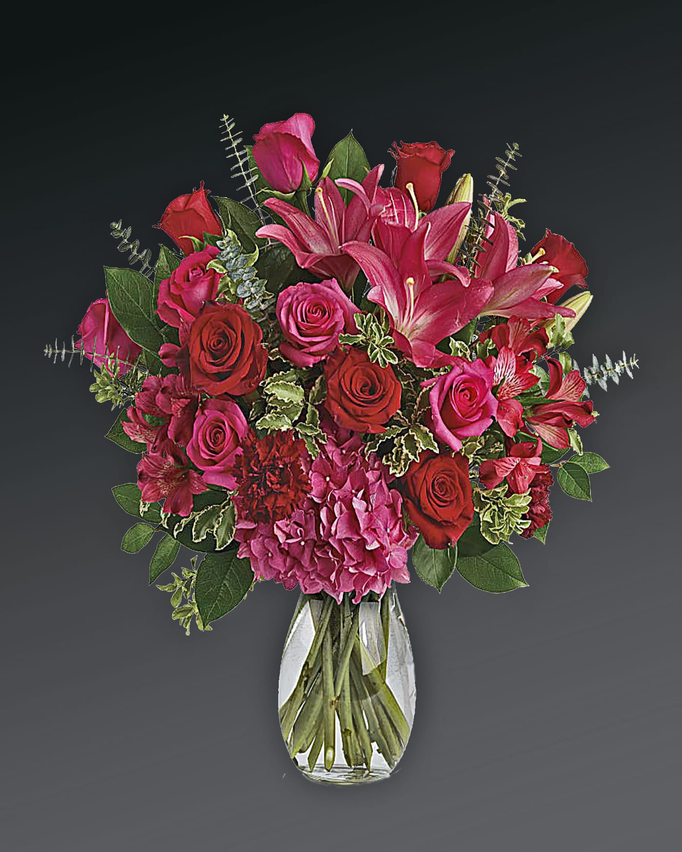 Love Struck Bouquet - There's no denying it, you're love struck! Shout it from the rooftops with this dramatic bouquet of hot pink hydrangea, roses and lilies. This luxe arrangement includes pink hydrangea, hot pink roses, red roses, dark pink asiatic lilies, dark pink alstroemeria, maroon carnations, pitta negra, spiral eucalyptus, and lemon leaf. Delivered in a glass jordan vase. Orientation: All-Around