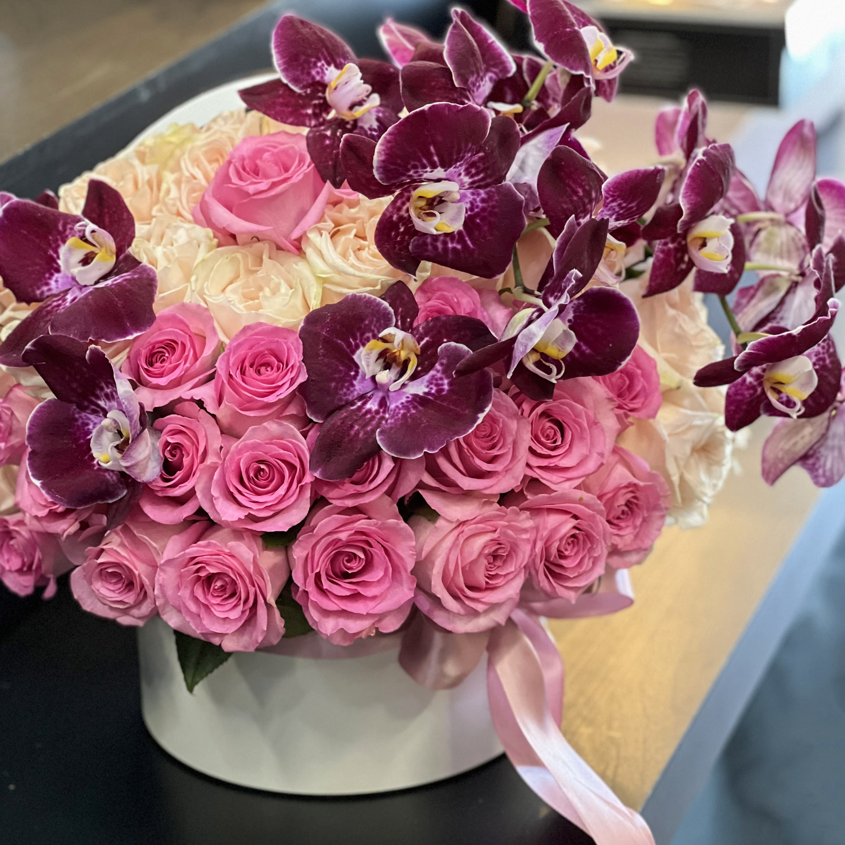 Violet Delight - Luxurious arrangement with 75 and above peach and pink roses with phalaenopsis orchids accent, arranged in a box. 