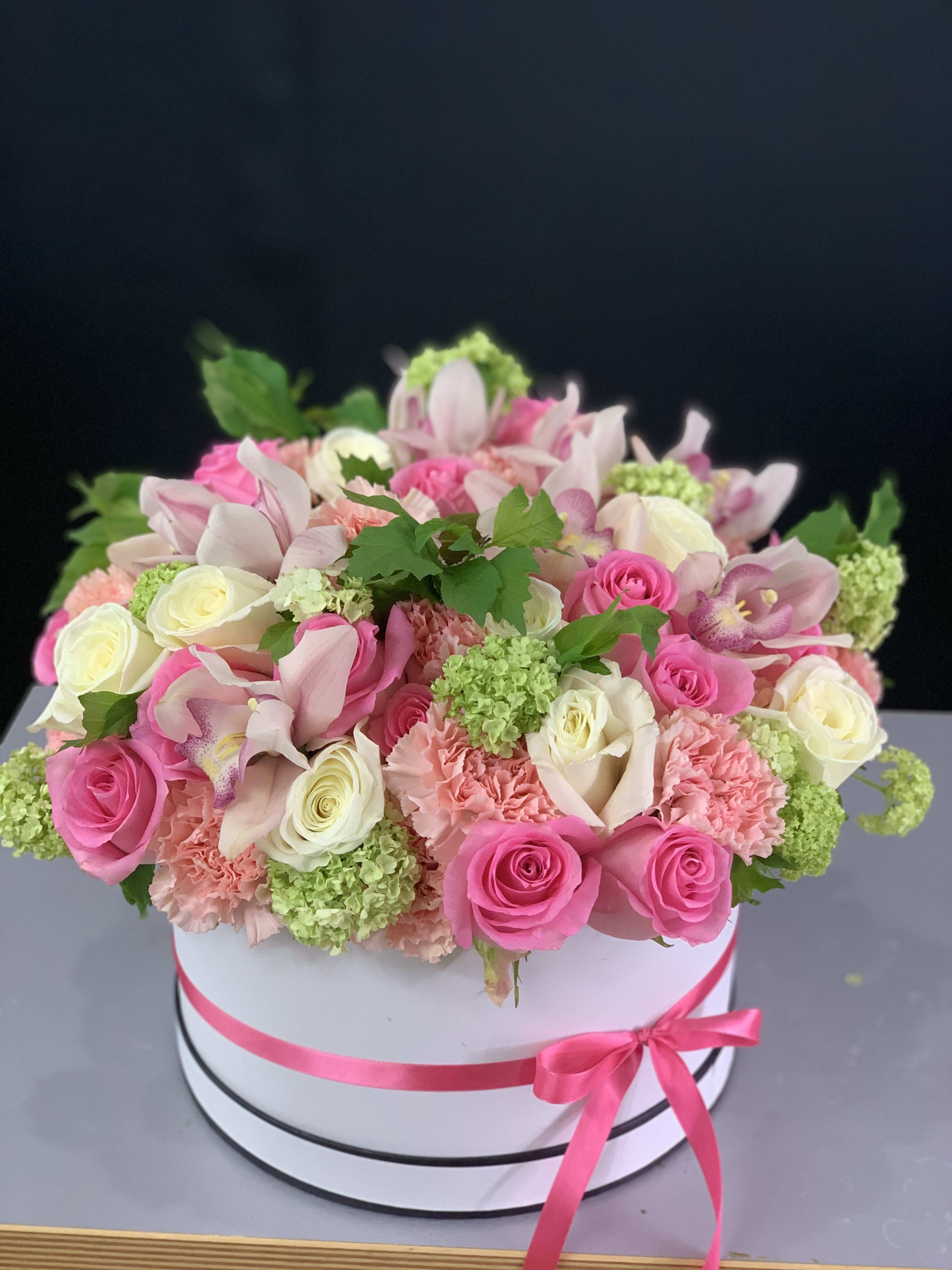Elegants. Hat Box Design in light pink colors - Delicate flower arrangement with pink roses, white cymbidium and mix seasonal flowers. Perfect flower present for any occasion. 