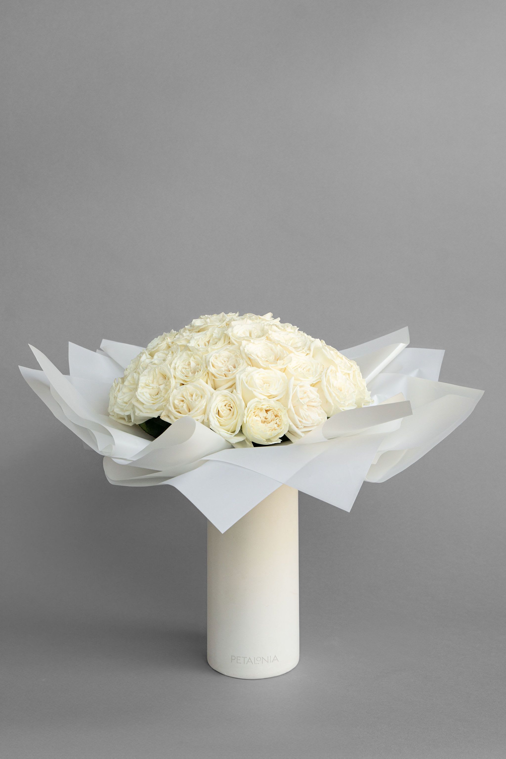 Classic 48 White Roses in a Signature Petalonia Vase and Tote - Experience pure elegance with Petalonia's 48 fresh-cut roses—beautifully arranged in our signature vase, wrapped in trendy Korean paper, and delivered in a stylish Petalonia tote, adding the perfect touch of luxury to any occasion.  Vase Dimensions 5.5” x 11.8”