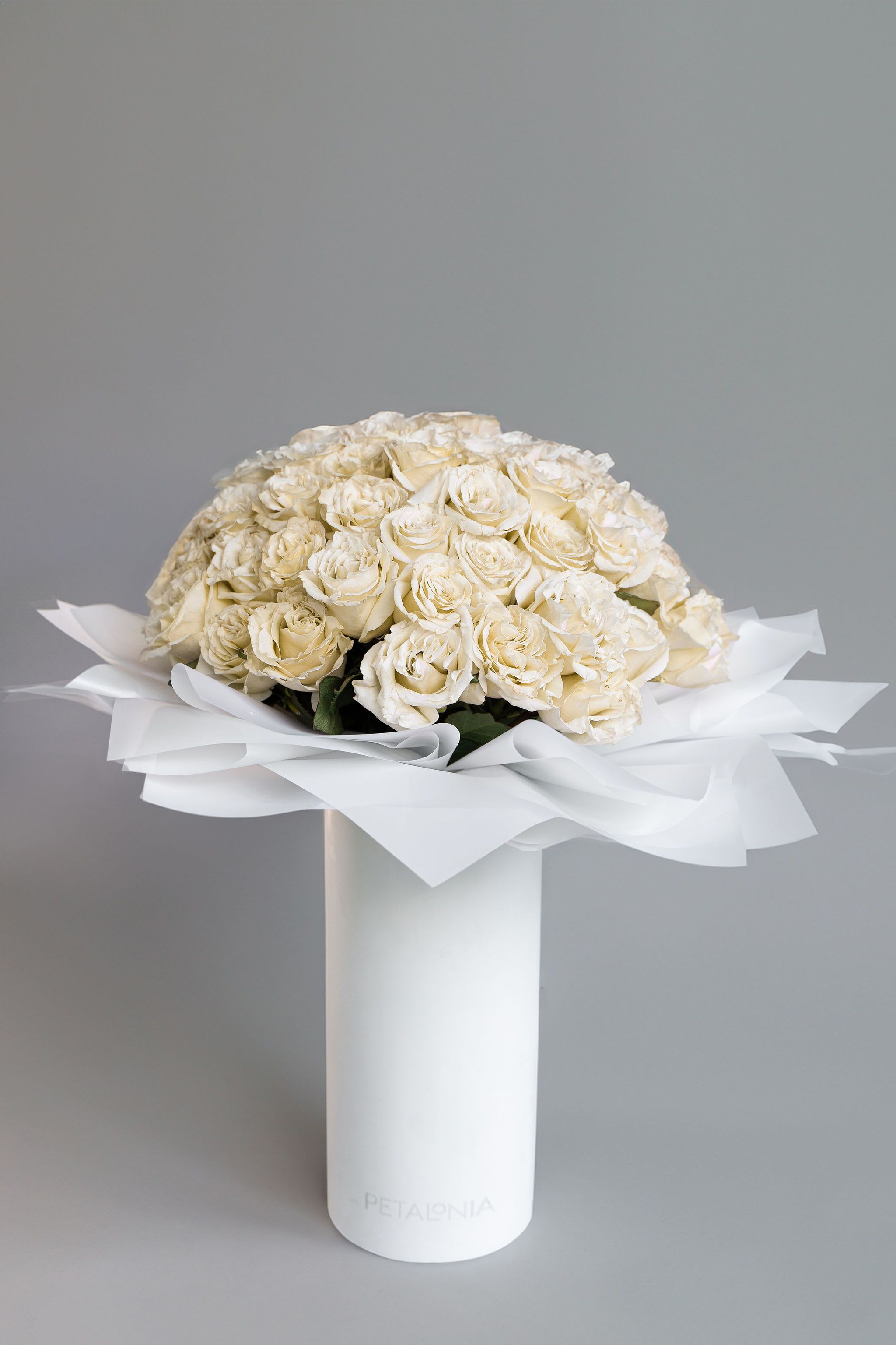 Classic 72 White Roses in a Signature Petalonia Vase with Tote - Experience pure elegance with Petalonia's 72 fresh-cut roses—beautifully arranged in our signature vase, wrapped in trendy Korean paper, and delivered in a stylish Petalonia tote, adding the perfect touch of luxury to any occasion.  Vase Dimensions 7.5” x 16”