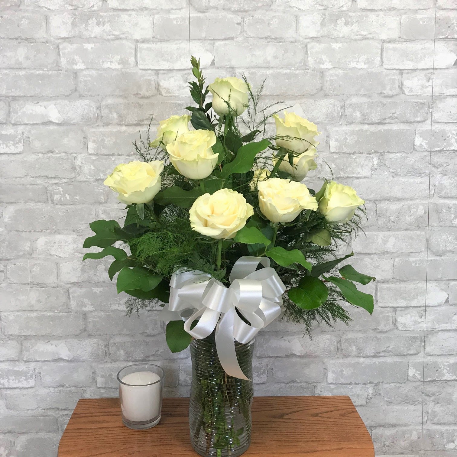 Classic Dozen White Roses FG103W - One Dozen of beautiful, romantic white roses in clear glass vase. Deluxe -- includes premium foliage. Premium -- includes premium foliage and premium accent flowers.  Approximately 27&quot; H x 15&quot; W