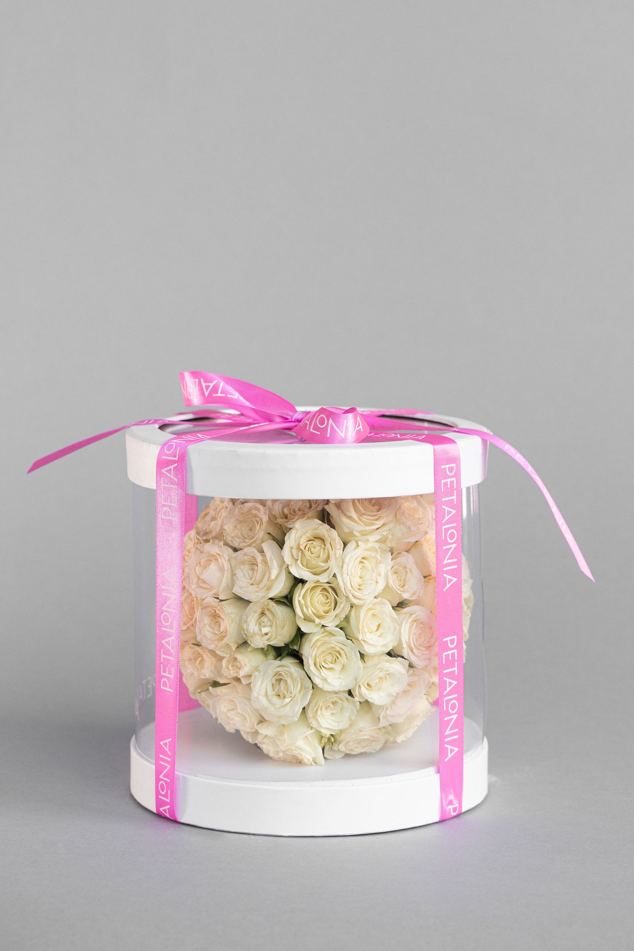 White Mini Rose Arrangement in a Clear Box - A gift and flower in one, this exquisite spherical arrangement of mini roses is elegantly presented in a clear box, showcasing its beauty from every angle. A perfect ready-to-gift piece, combining charm and sophistication for any occasion.  Box Dimensions 8&quot; x 8&quot; x 8' Flower Arrangement Dimensions Approx. 6” x 6” x 6”