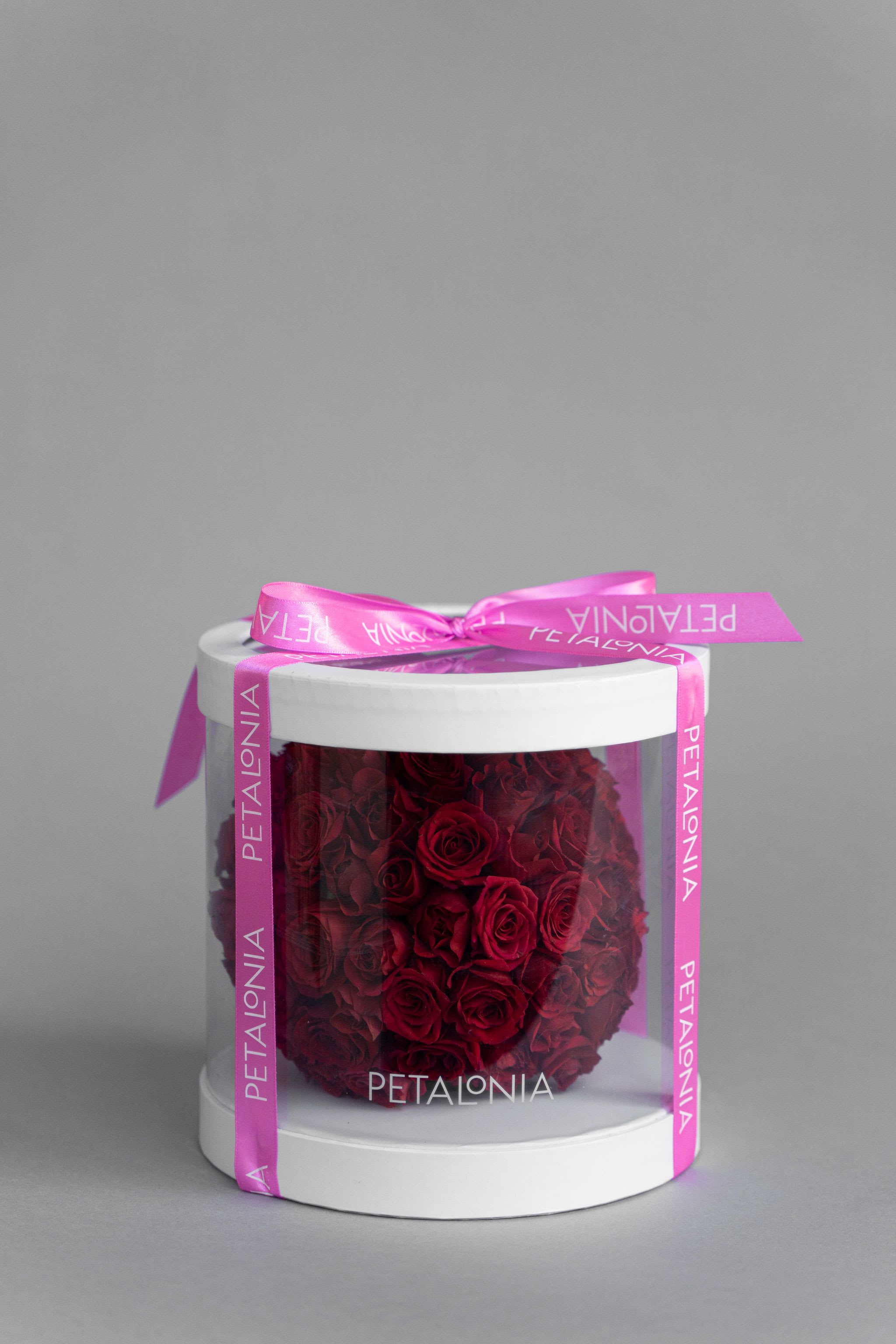  Red Mini Rose Arrangement in a Clear Box - A gift and flower in one, this exquisite spherical arrangement of mini roses is elegantly presented in a clear box, showcasing its beauty from every angle. A perfect ready-to-gift piece, combining charm and sophistication for any occasion.  Box Dimensions 8&quot; x 8&quot; x 8' Flower Arrangement Dimensions Approx. 6” x 6” x 6”