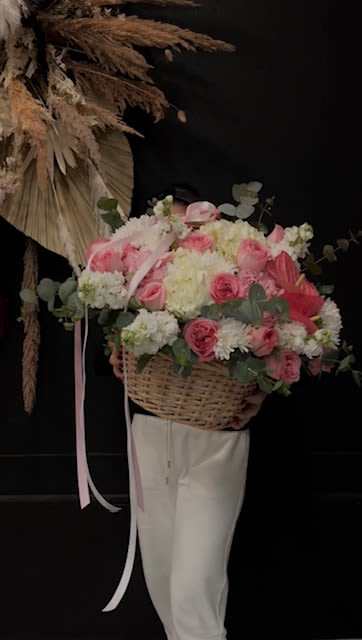 Blushin Pink - Wicker Basket filled with Designers Choice of an Array of Fresh Cut Pink Tone such as, Garden Roses,  Double Stock, Ranunculus, Carnations and more. Topped with Accent Bow (Florals placed in wet foam infused with floral food preservative to extend life of florals). (basket shape and color vary)