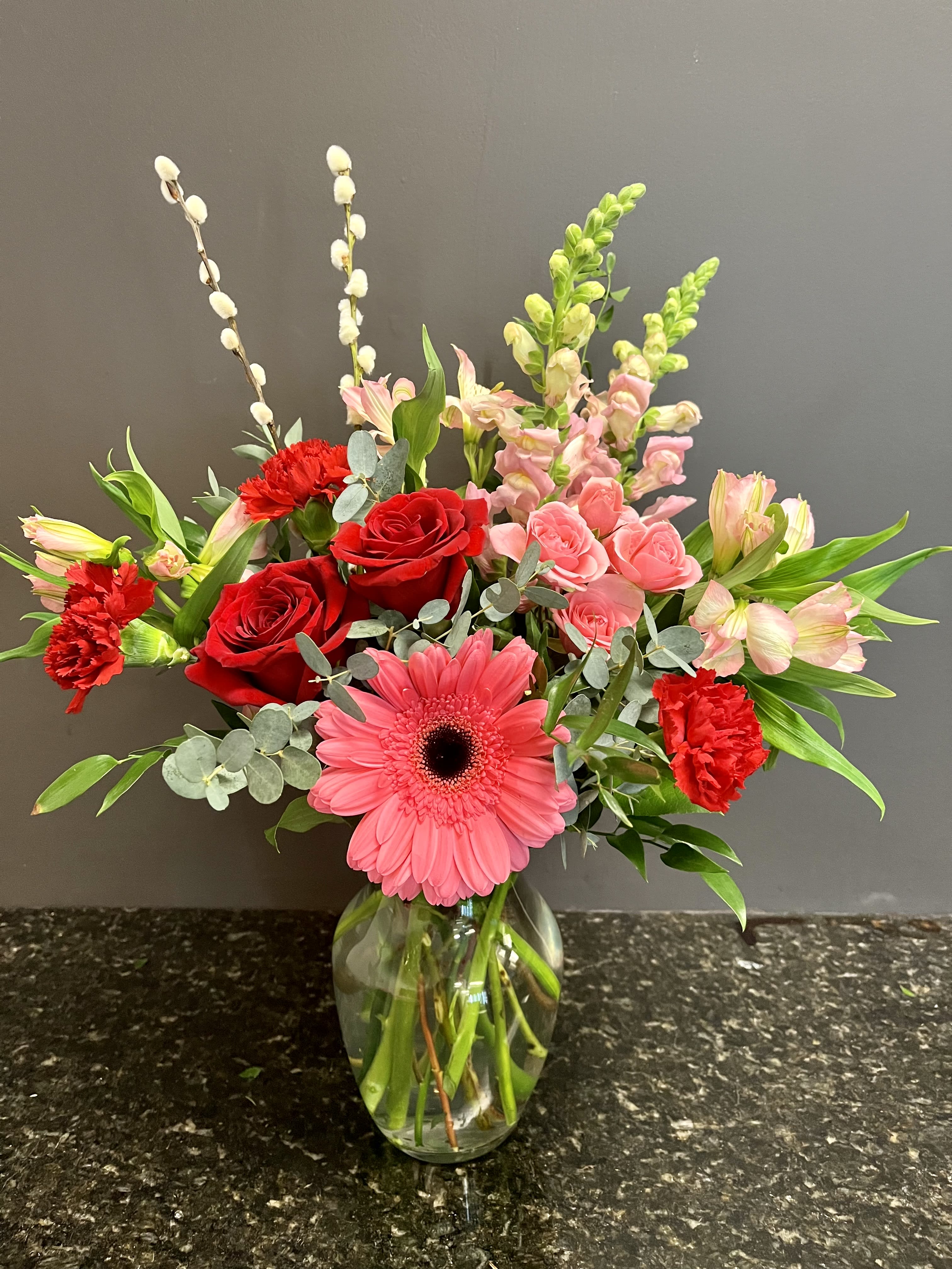 Cupid's Kiss Cupid's Kiss - a mix of pink and red flowers to include roses, spray roses, snap dragons, alstroemeria, gerber daisy and carnations. accented with fresh spring twigs